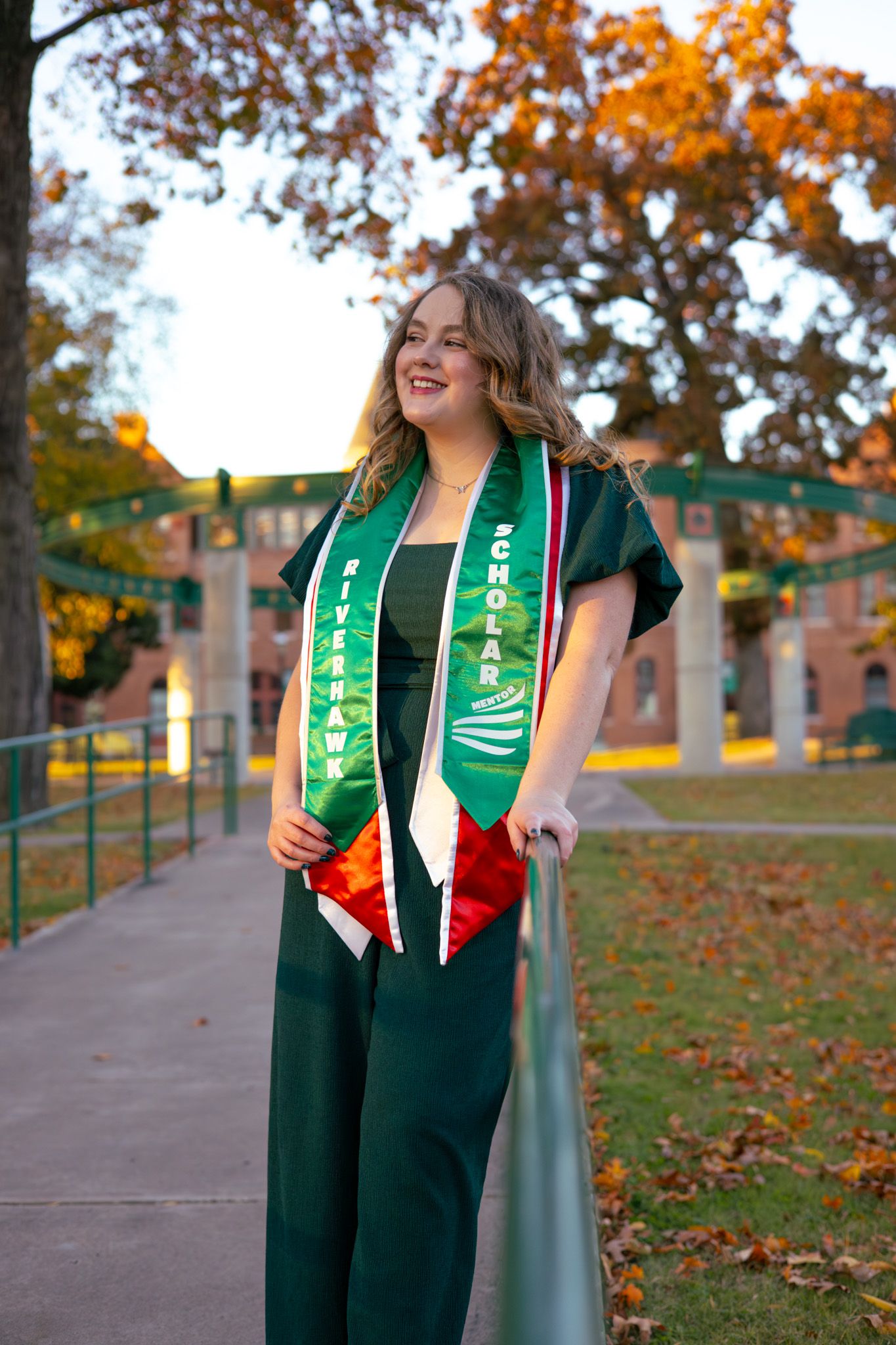 A young adult girl wearing graduation regalia and smiles away from the camera.