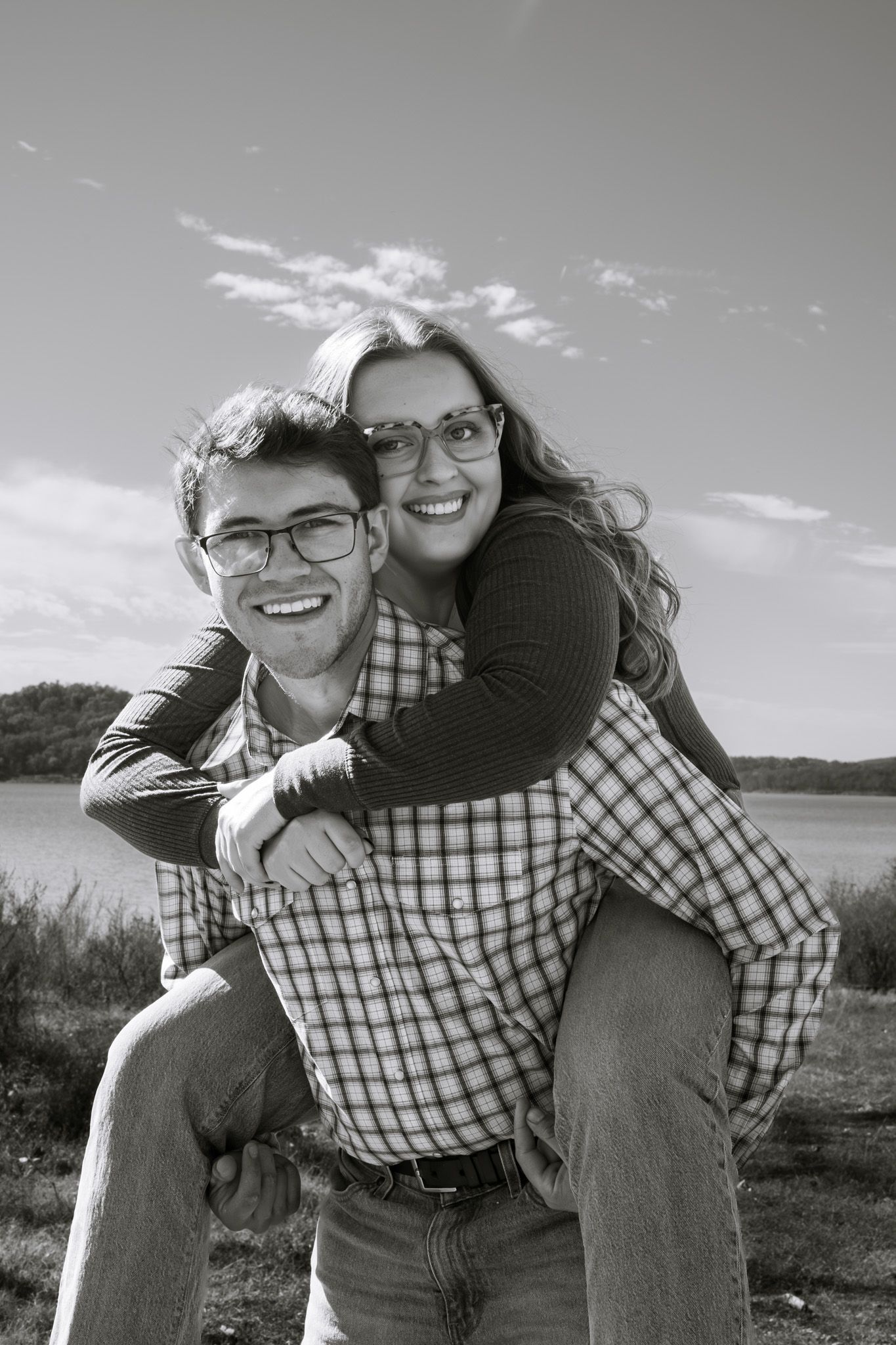 A piggybacked young adult on her boyfriend. Both are smiling, and the image is in black and white.