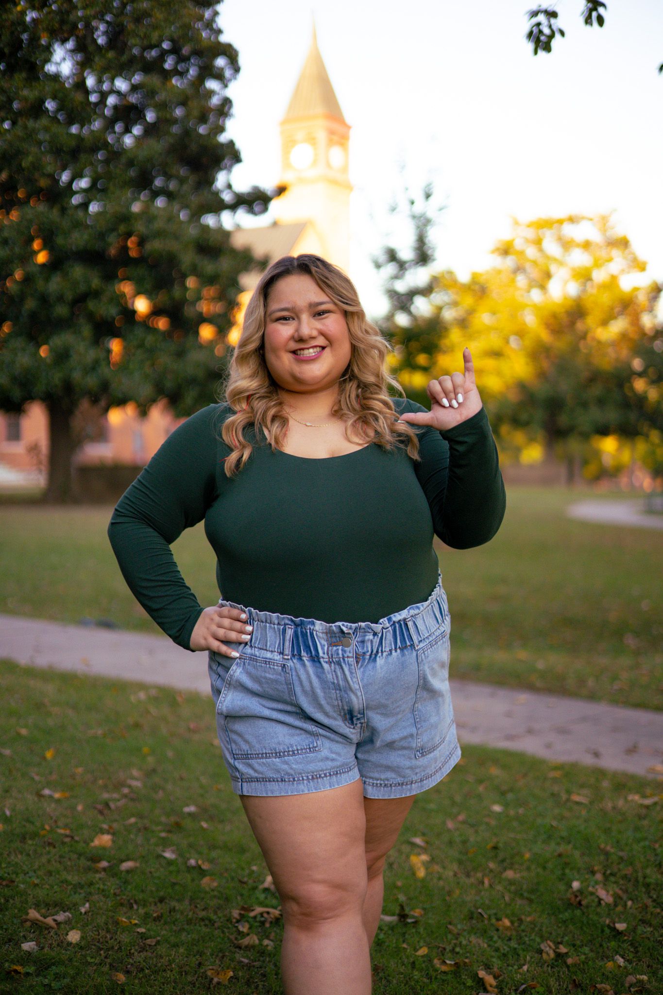 A young adult girl holding up her university hand sign 