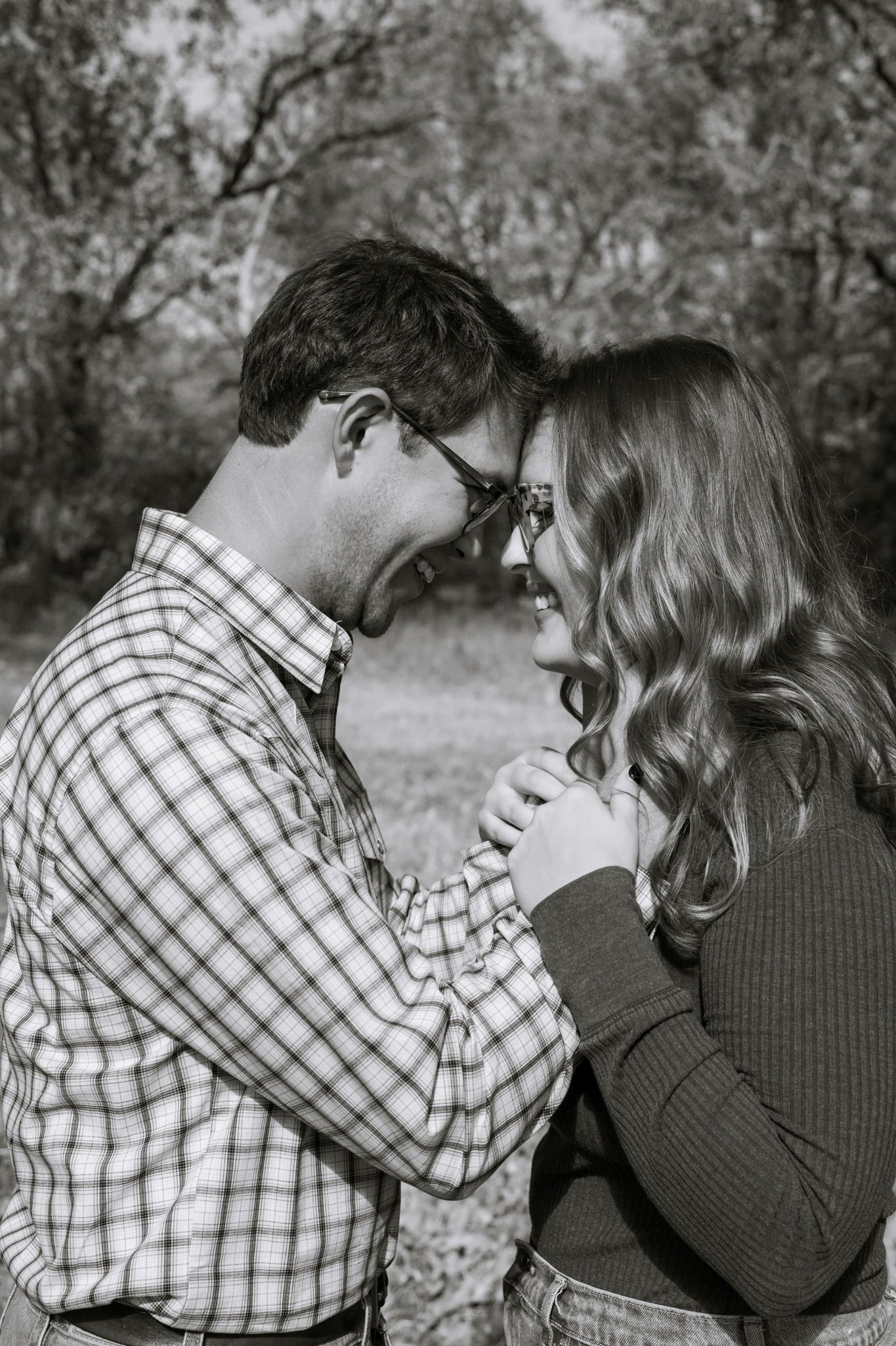 A young adult couple holds each other close with big grins. The image is in black and white.