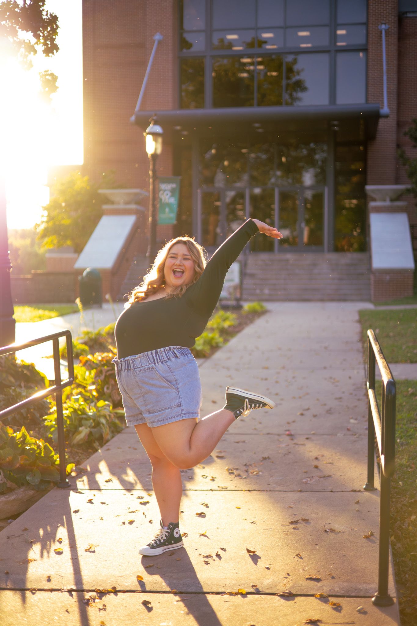A young adult girl jumping with joy on her college campus.