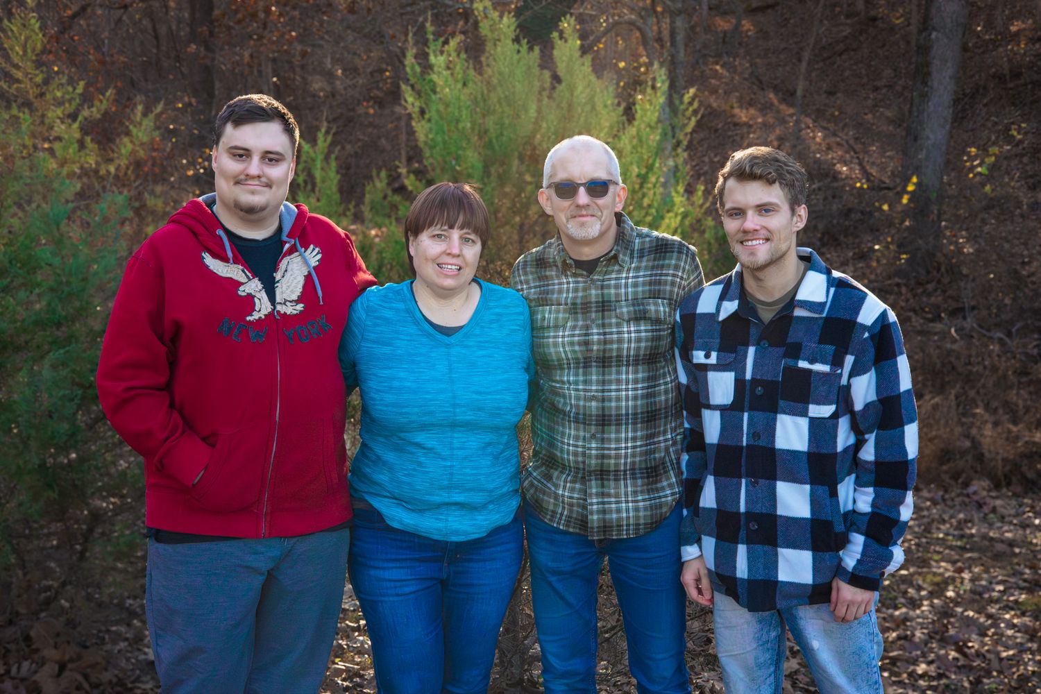 A family of four facing the camera with big smiles.
