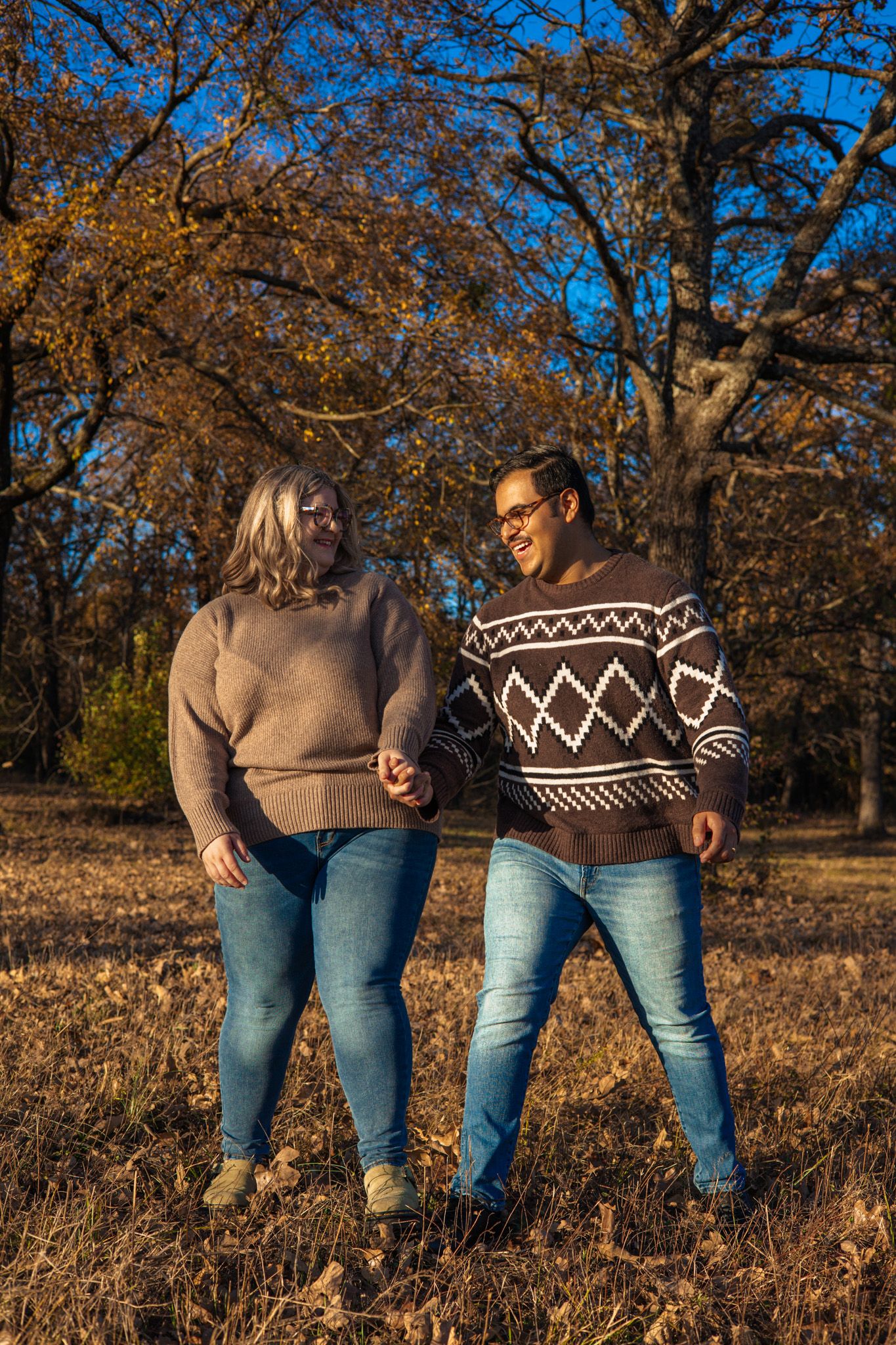 A young adult couple holding hands and laughing.