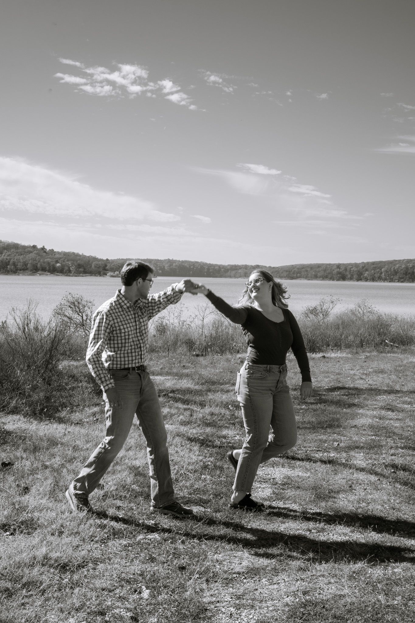 A young adult couple dances in front of a lake. The image is in black and white.