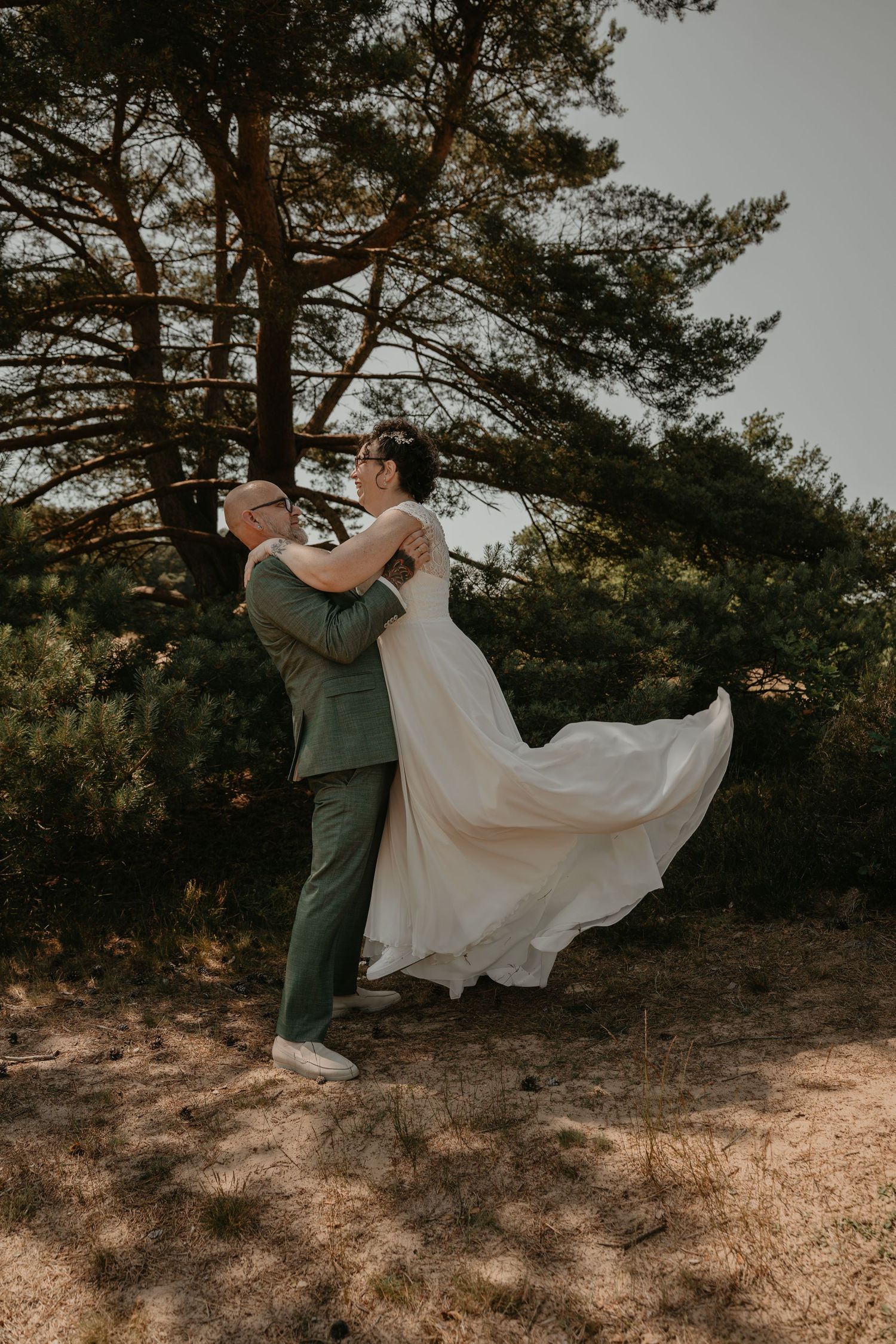 Bruidegom tilt zijn bruid op tijdens een romantische trouwshoot in de Zeegser Duinen