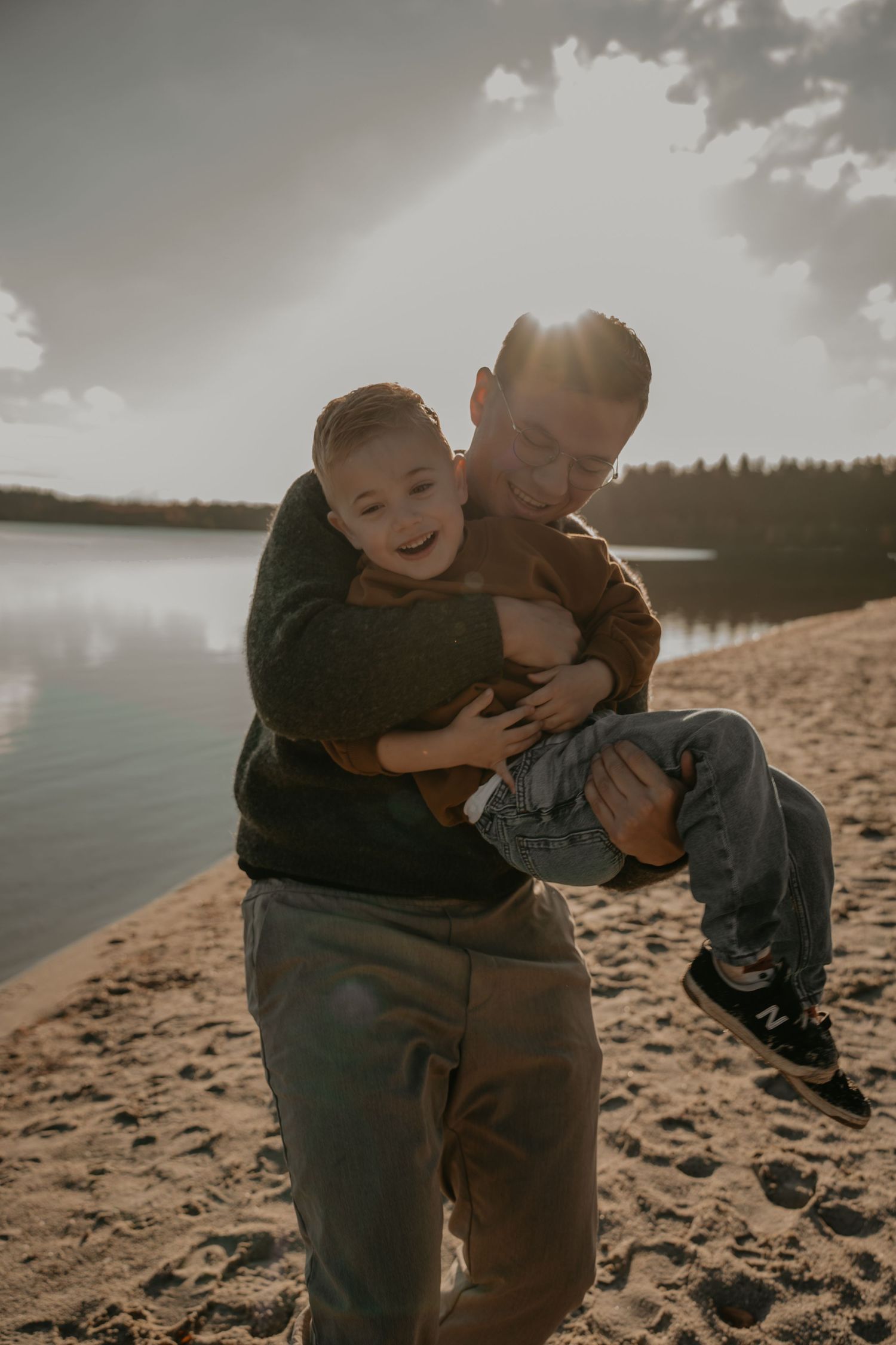 Spontane gezinsshoot op het strand in Drenthe met vader en kind in warm tegenlicht