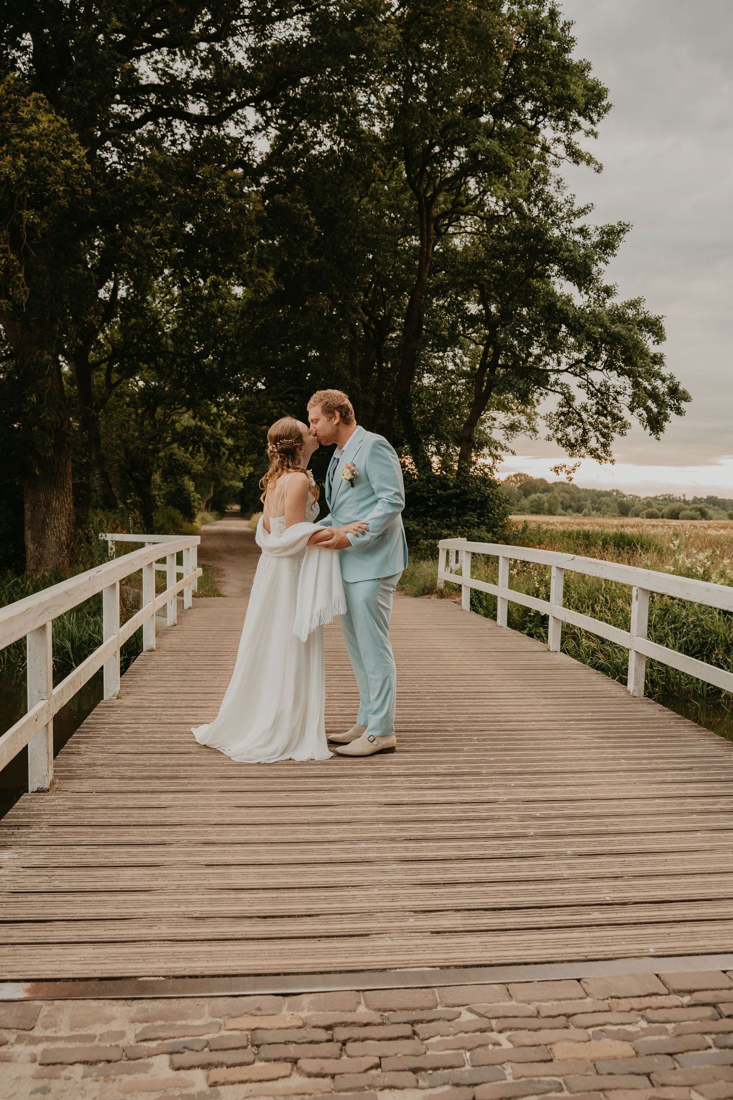 Romantische trouwfoto van een bruidspaar op een houten brug in Drenthe