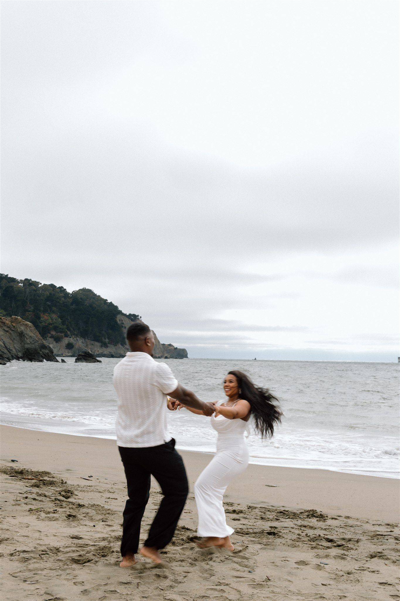 Couple posing for their engagement session at Baker Beach in San Francisco, California, captured by Makayla Miranda Photo