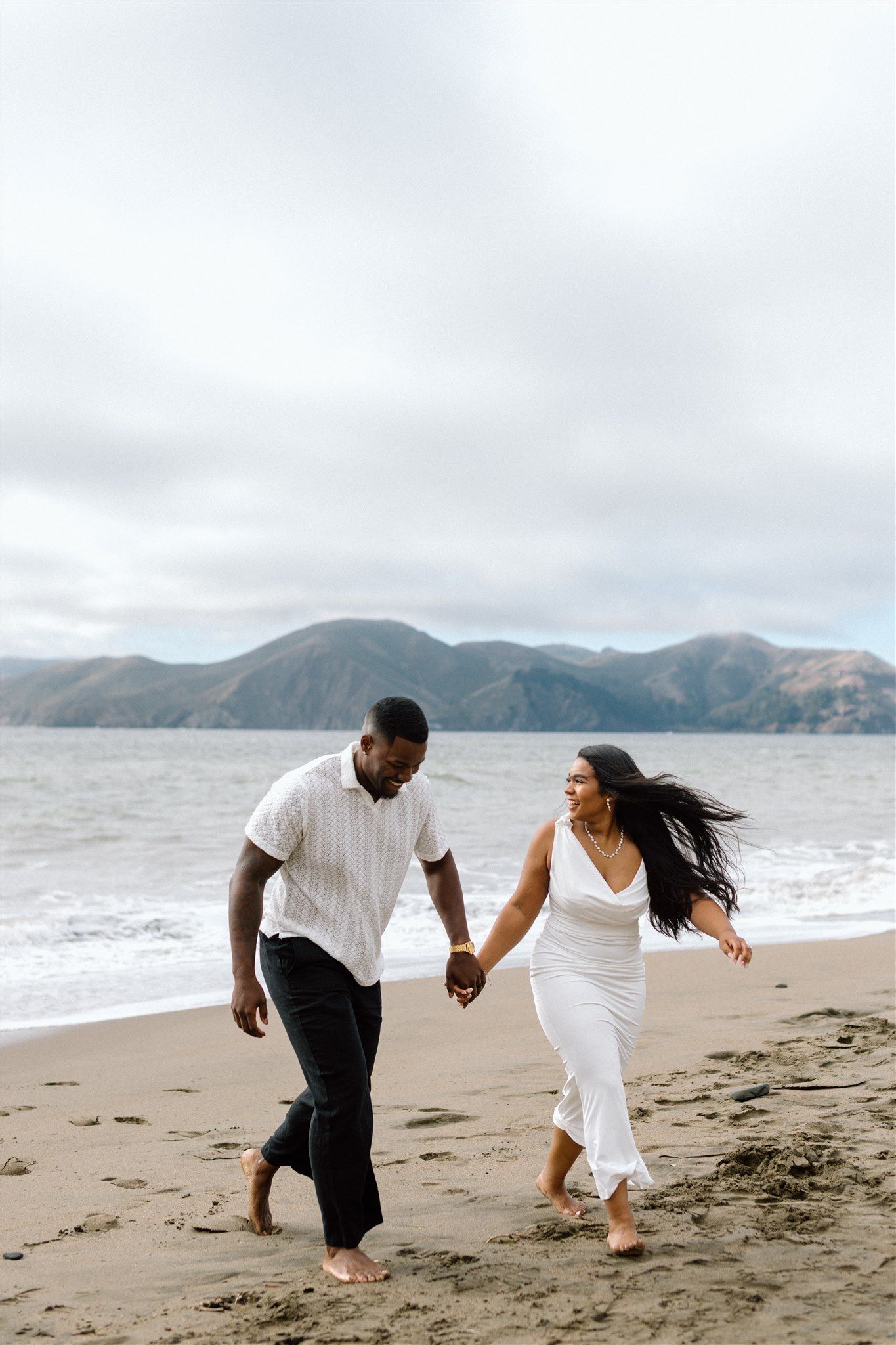 Couple posing for their engagement session at Baker Beach in San Francisco, California, captured by Makayla Miranda Photo