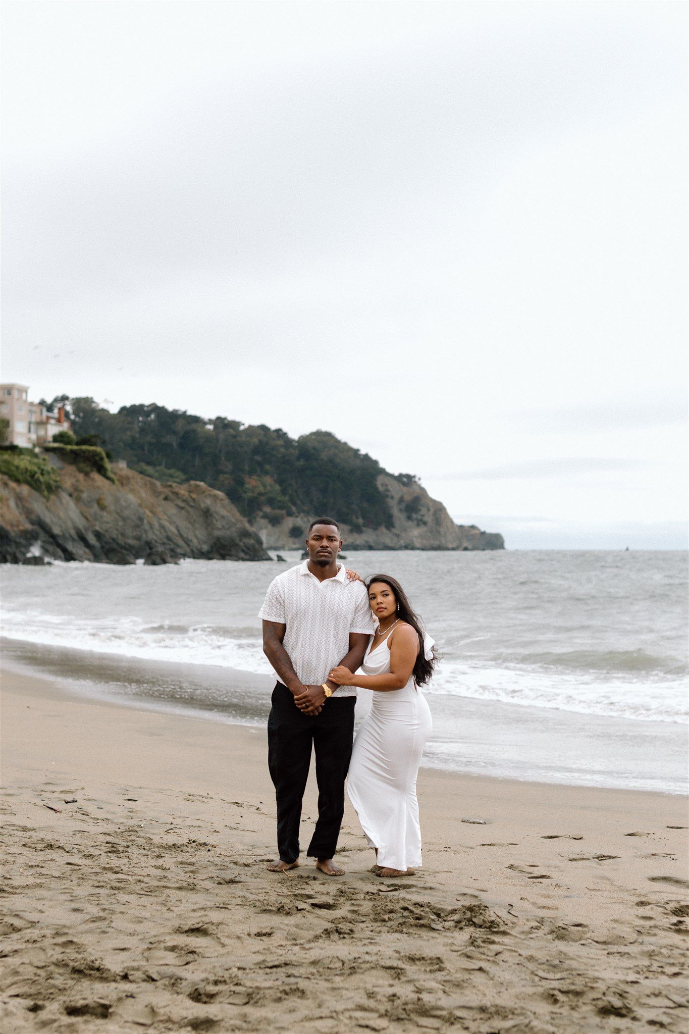 Couple posing for their engagement session at Baker Beach in San Francisco, California, captured by Makayla Miranda Photo.