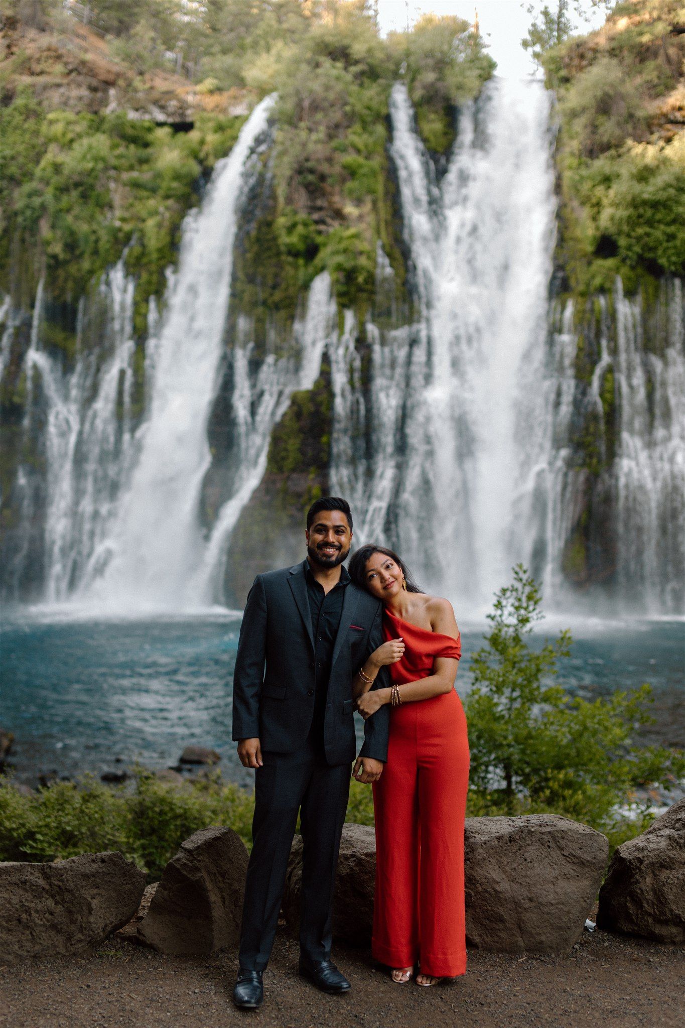 Couple posing for their engagement session at Burney Falls in Northern California, captured by Makayla Miranda Photo.