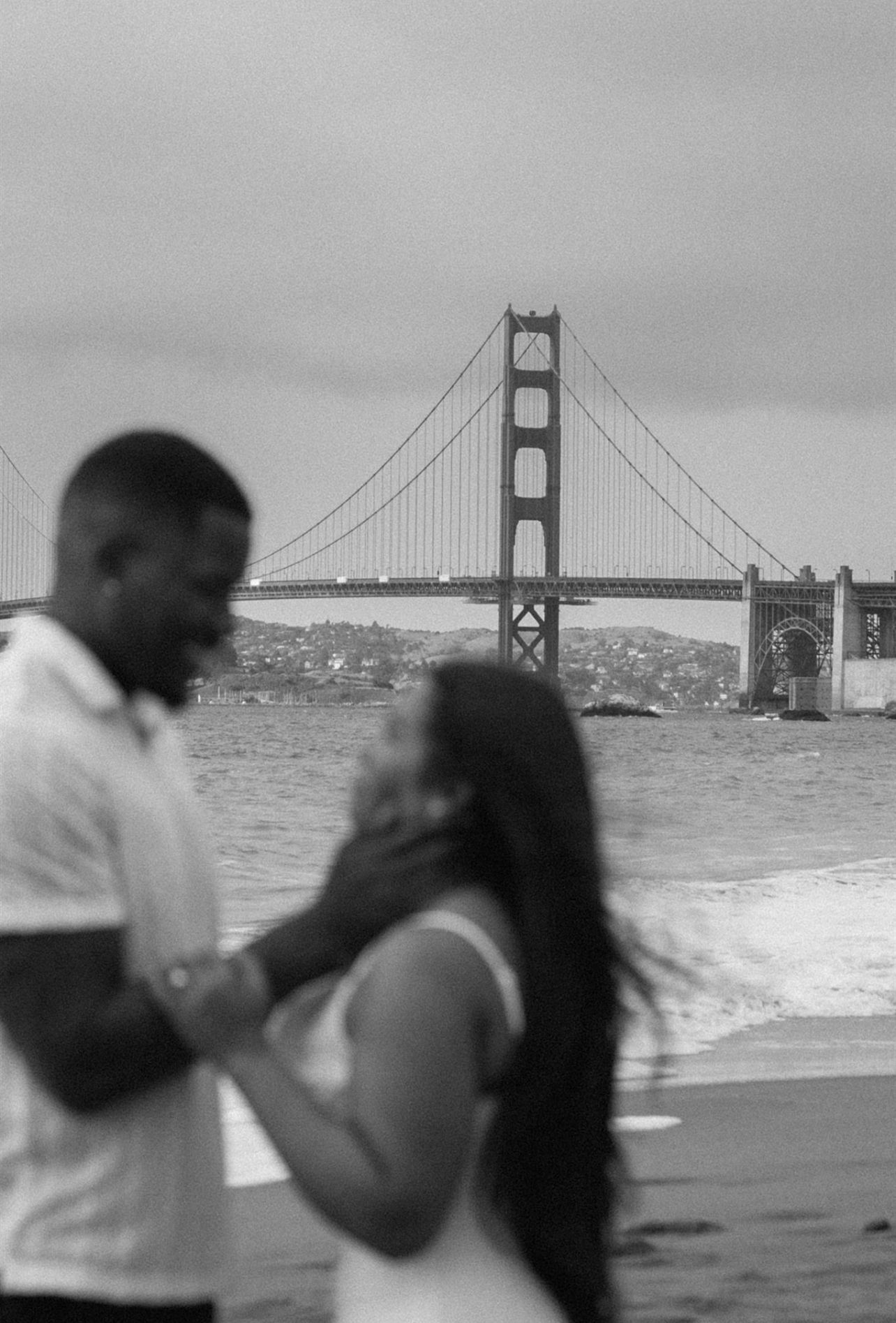 Couple posing for their engagement session at Baker Beach in San Francisco, California, captured by Makayla Miranda Photo