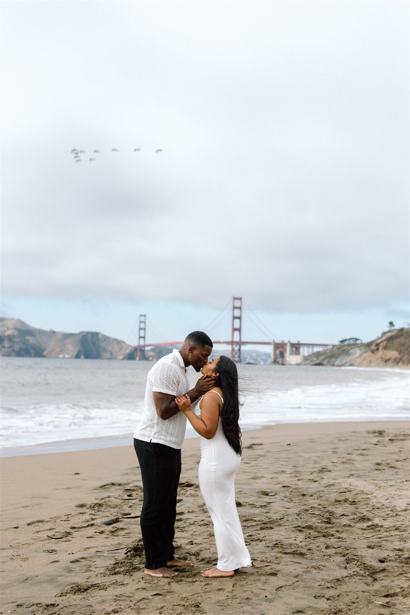 Couple posing for their engagement session at Baker Beach in San Francisco, California, captured by Makayla Miranda Photo