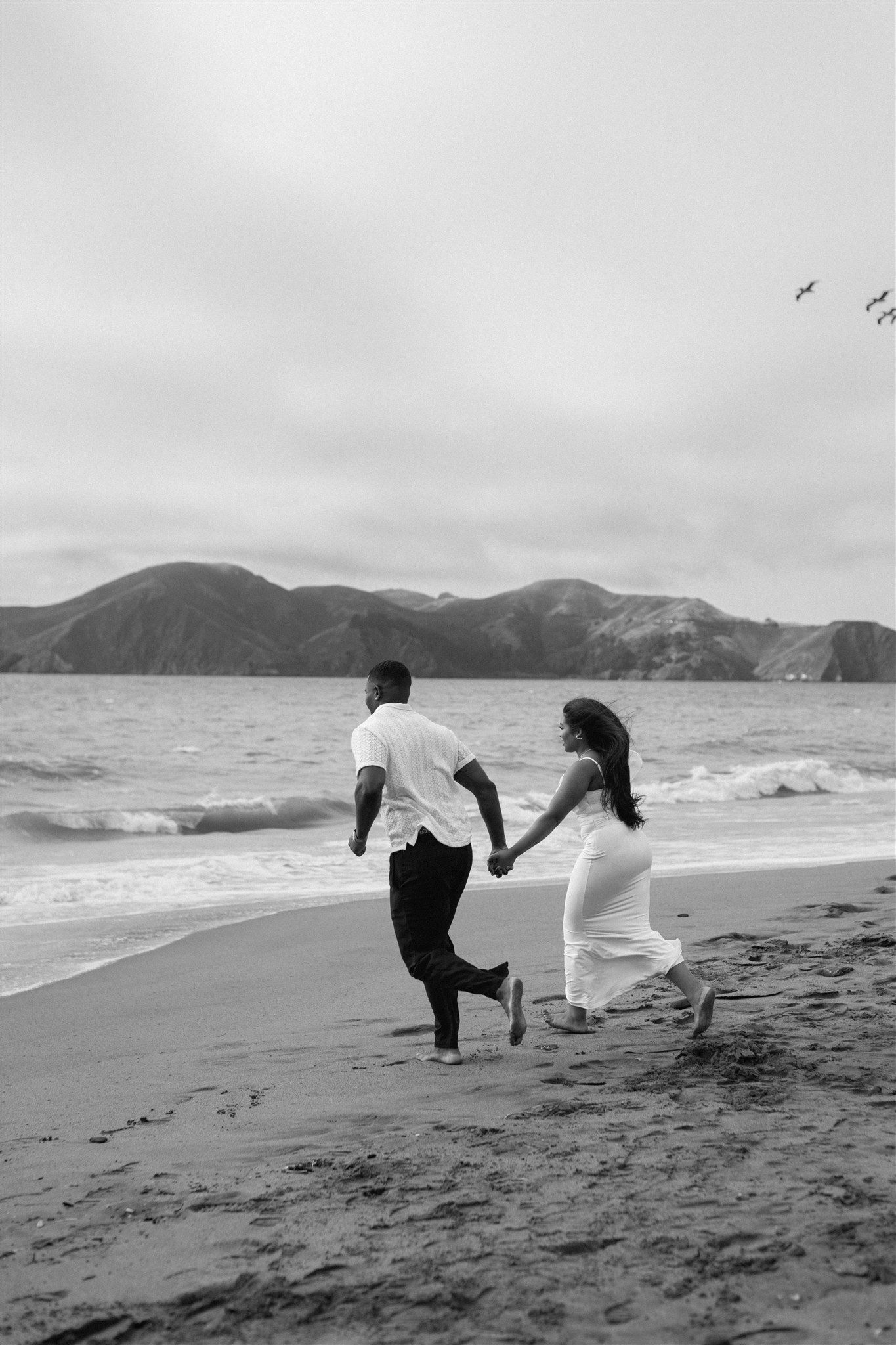 Couple posing for their engagement session at Baker Beach in San Francisco, California, captured by Makayla Miranda Photo