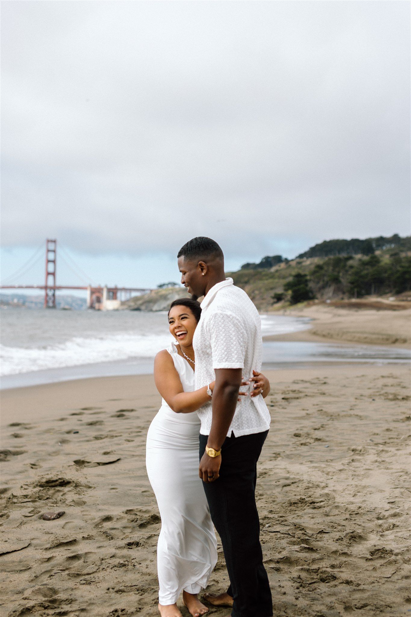 Couple posing for their engagement session at Baker Beach in San Francisco, California, captured by Makayla Miranda Photo