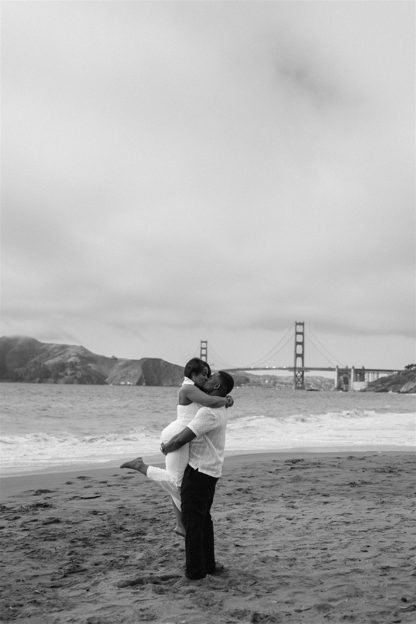 Couple posing for their engagement session at Baker Beach in San Francisco, California, captured by Makayla Miranda Photo