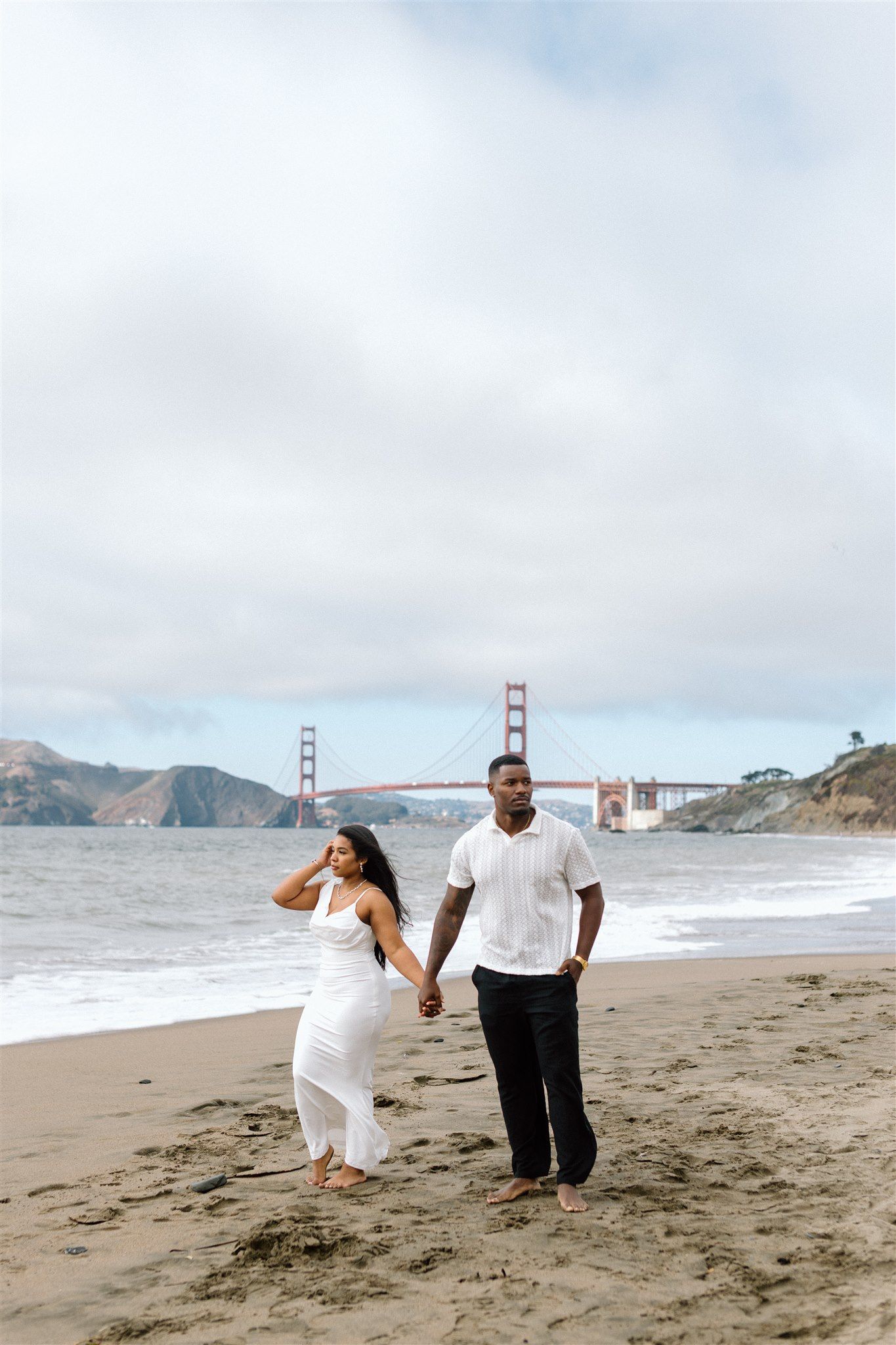 Couple posing for their engagement session at Baker Beach in San Francisco, California, captured by Makayla Miranda Photo