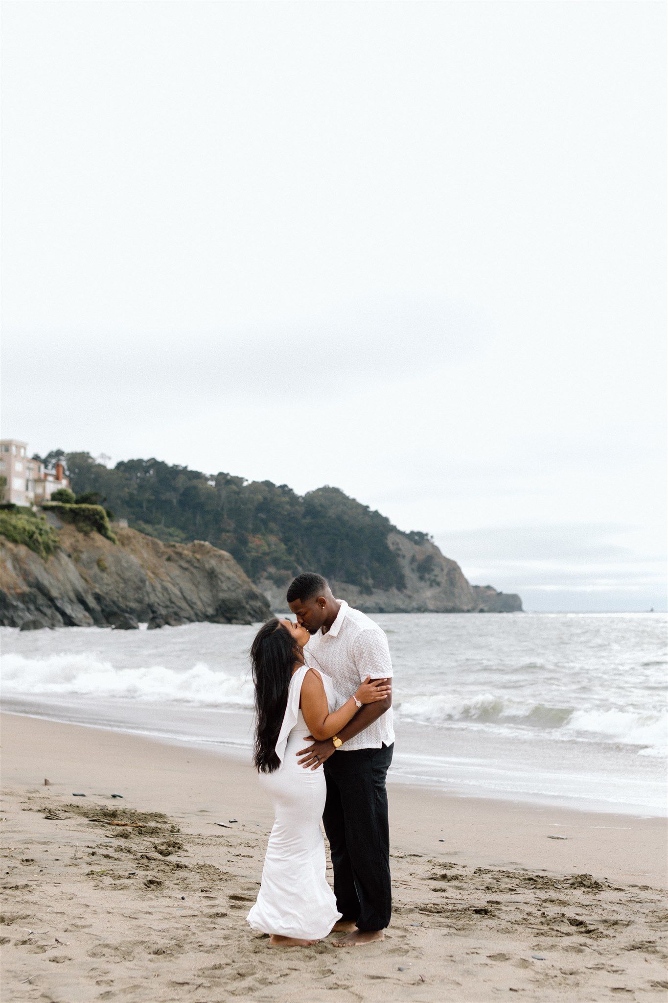 Couple posing for their engagement session at Baker Beach in San Francisco, California, captured by Makayla Miranda Photo
