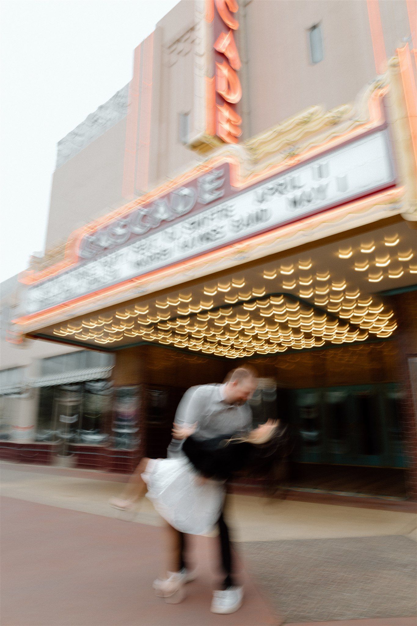 Couple posing for a styled engagement session in front of a theater, captured by Makayla Miranda Photo.