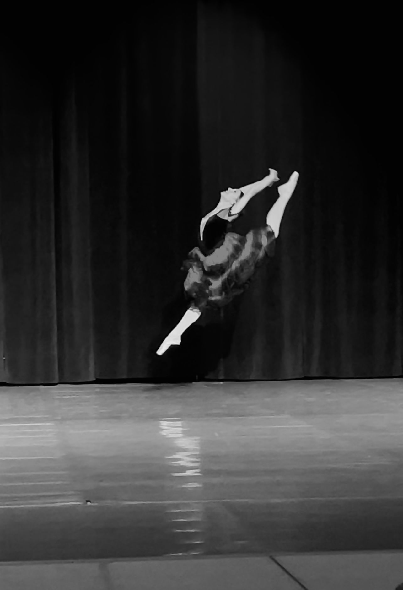 A dramatic black and white photo sequence captures a dancer performing an aerial flip on a dark stage.