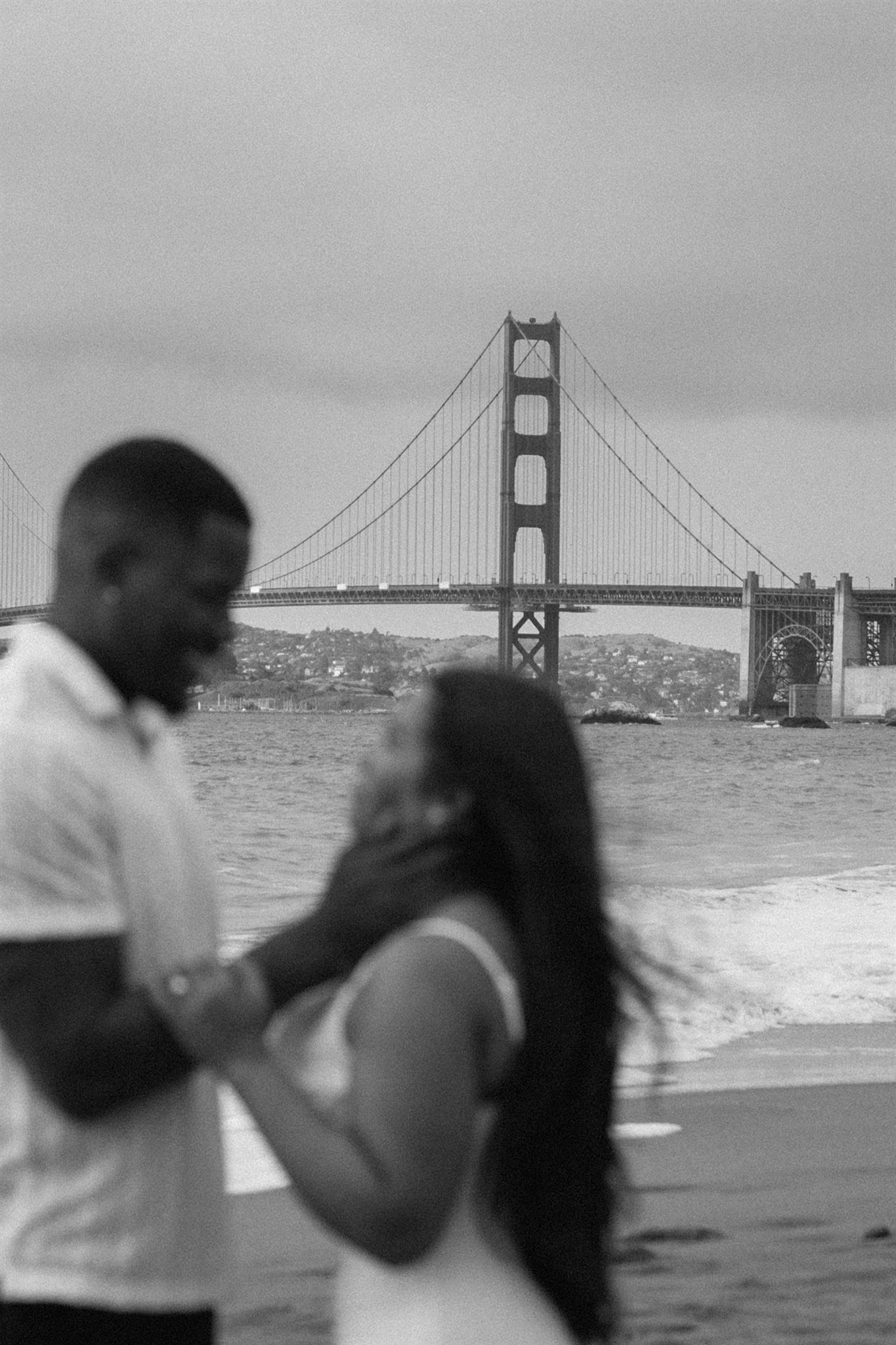 Couple posing for their engagement session at Baker Beach in San Francisco, California, captured by Makayla Miranda Photo