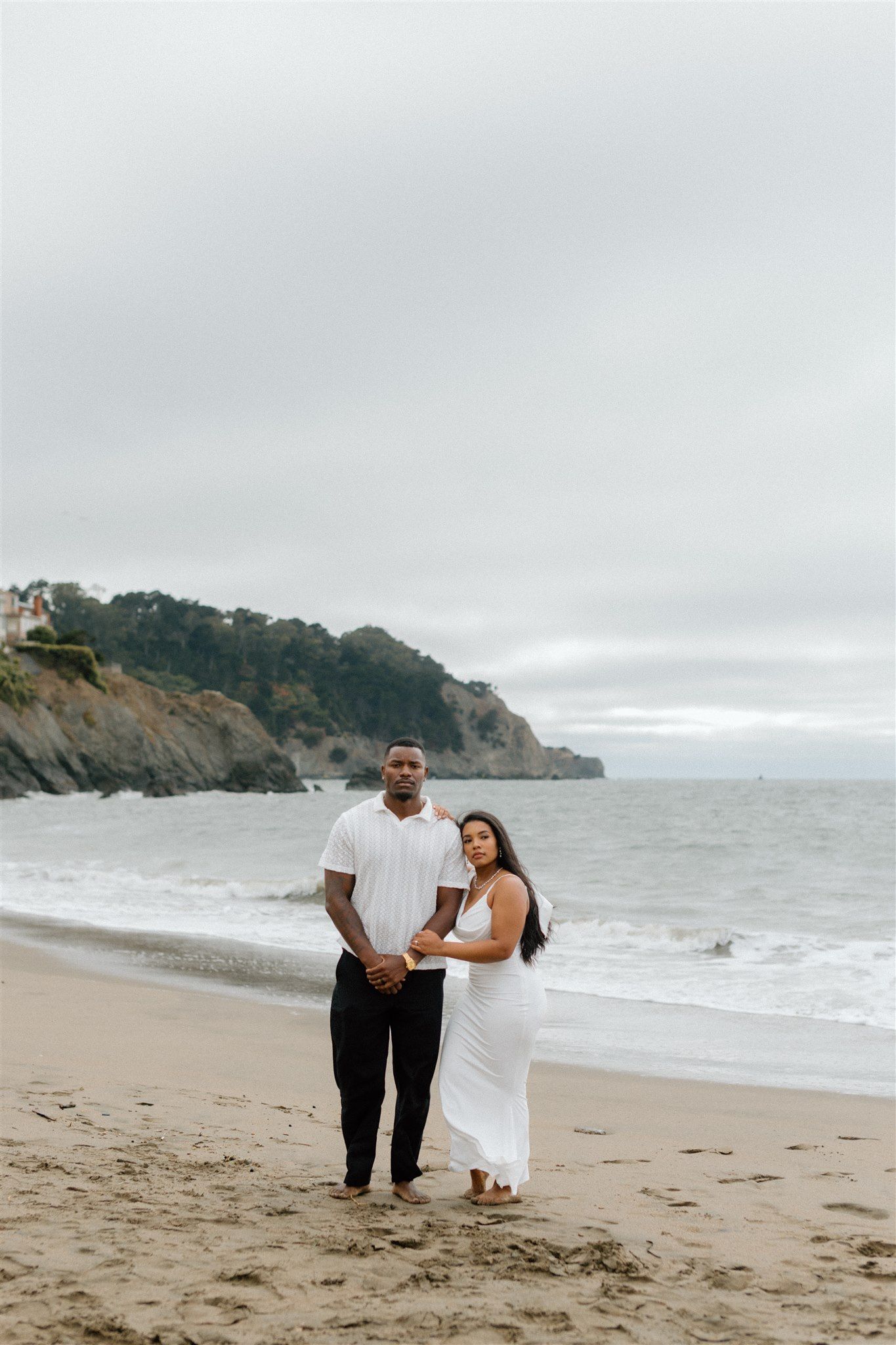 Couple posing for their engagement session at Baker Beach in San Francisco, California, captured by Makayla Miranda Photo