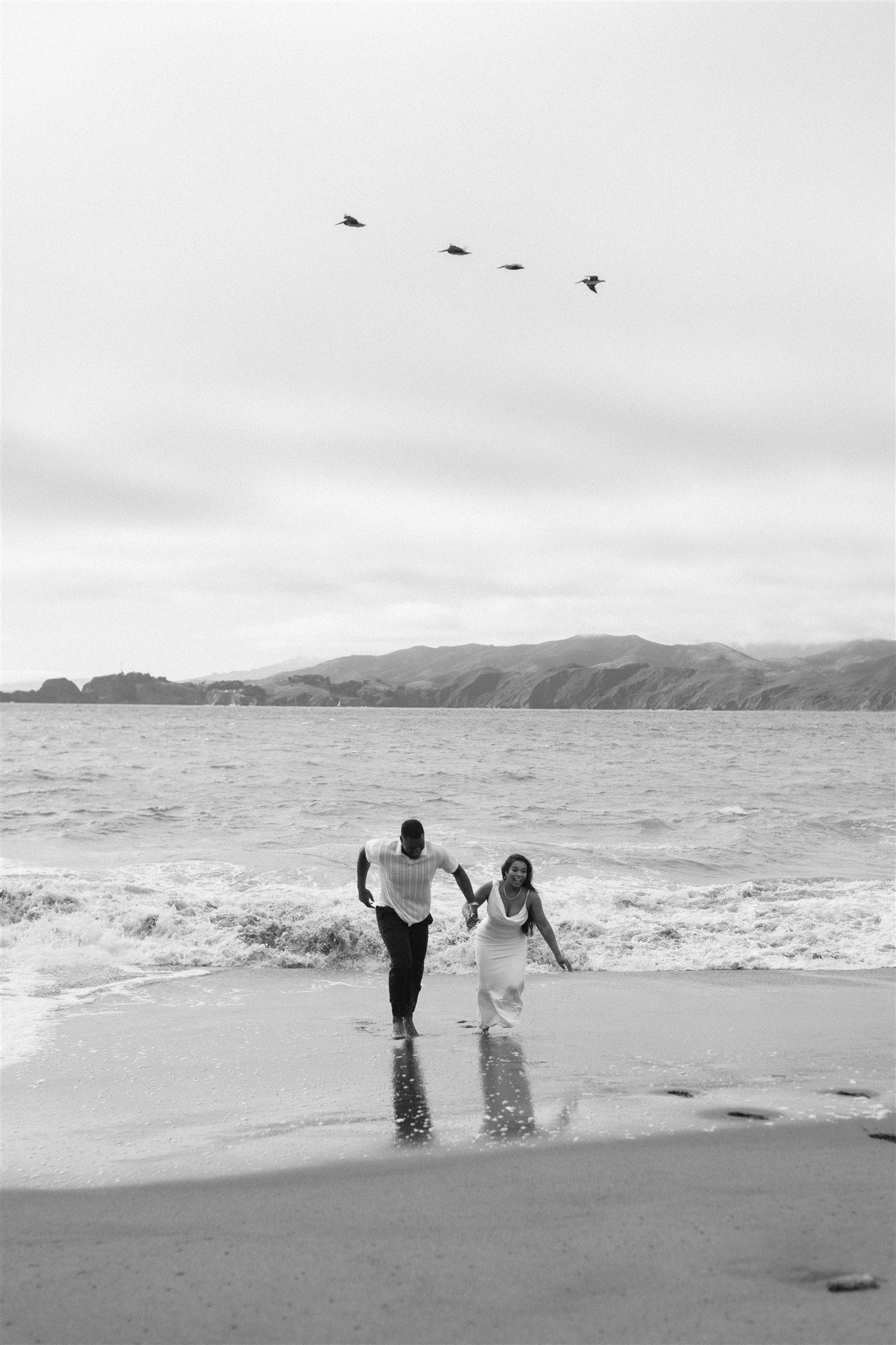 Couple posing for their engagement session at Baker Beach in San Francisco, California, captured by Makayla Miranda Photo