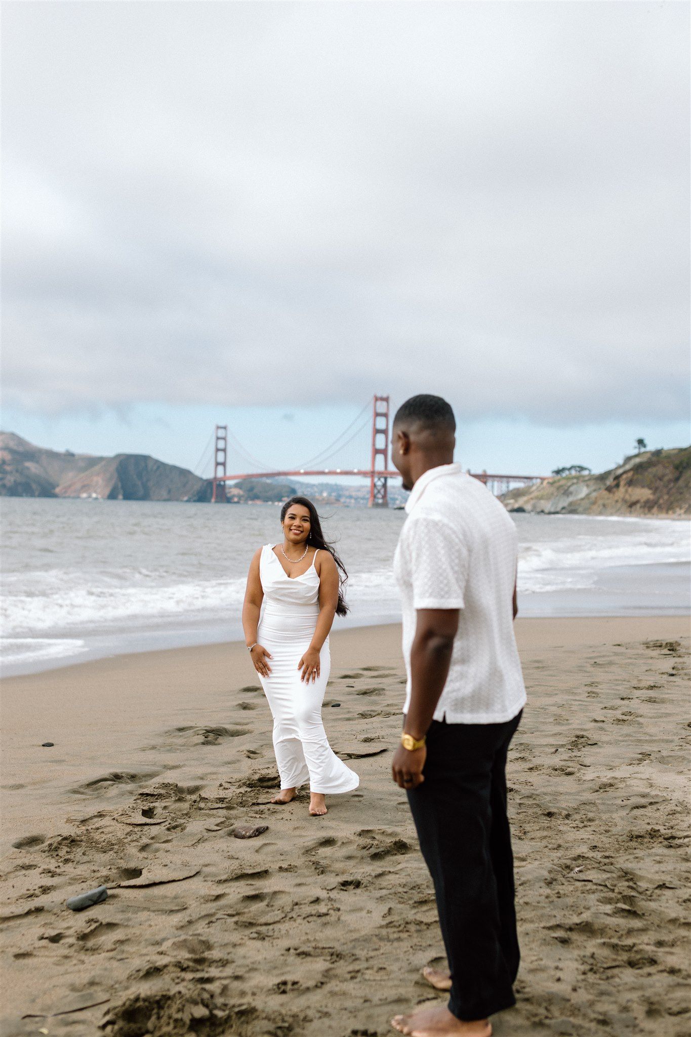 Couple posing for their engagement session at Baker Beach in San Francisco, California, captured by Makayla Miranda Photo