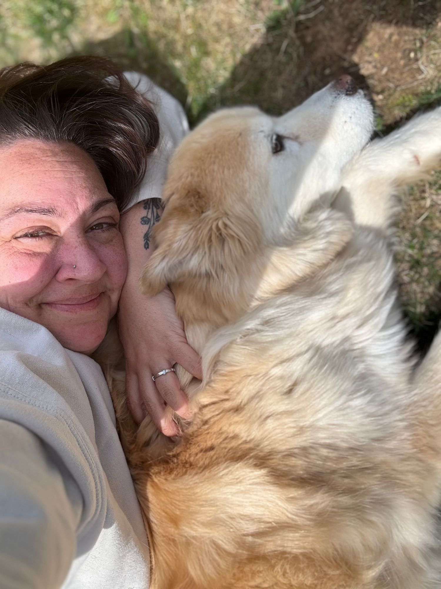A woman taking a selfie while cuddling with her fluffy golden Husky dog.