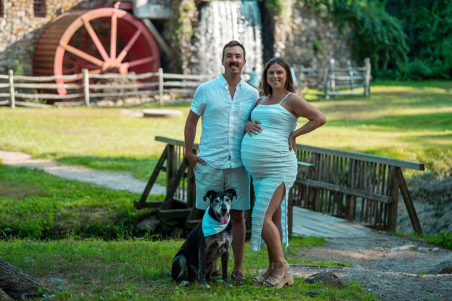 maternity family photo with dog in front of the grist mill at the Longfellow Wayside Inn in Sudbury, MA