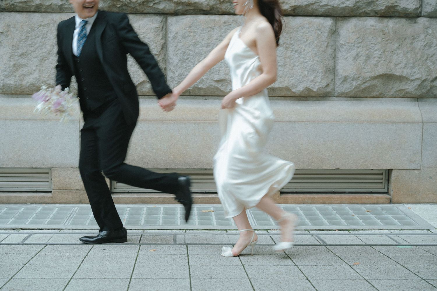 手をつないで駆け出すご夫婦の軽やかなポートレート