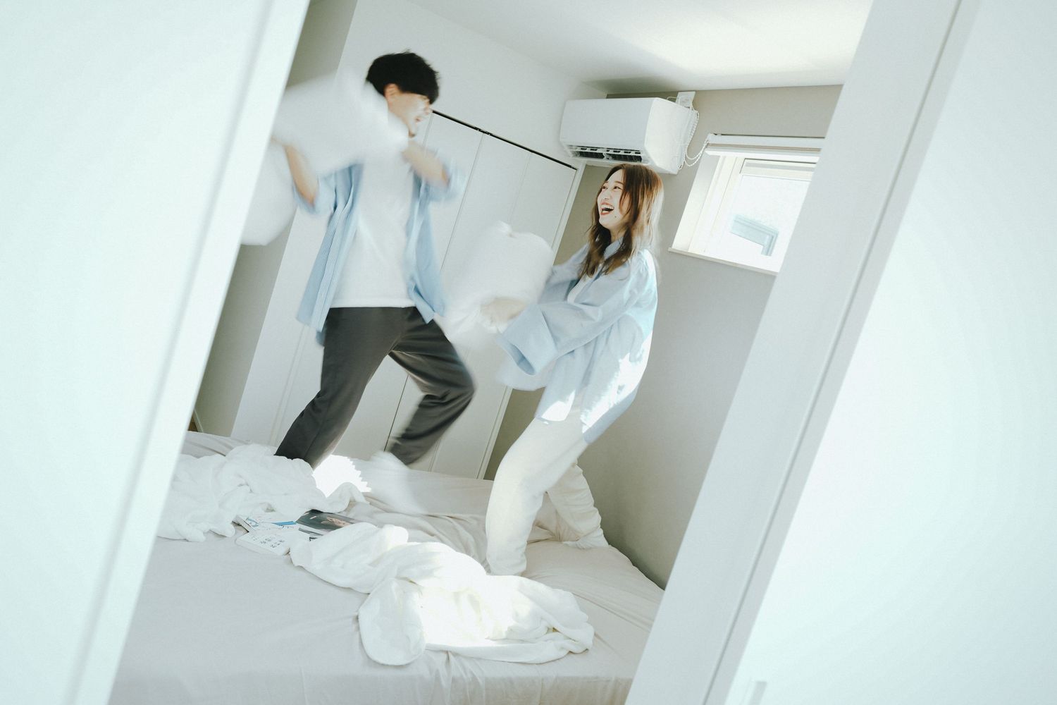 おうちで笑い合いながら枕投げをしているご夫婦の自然な写真