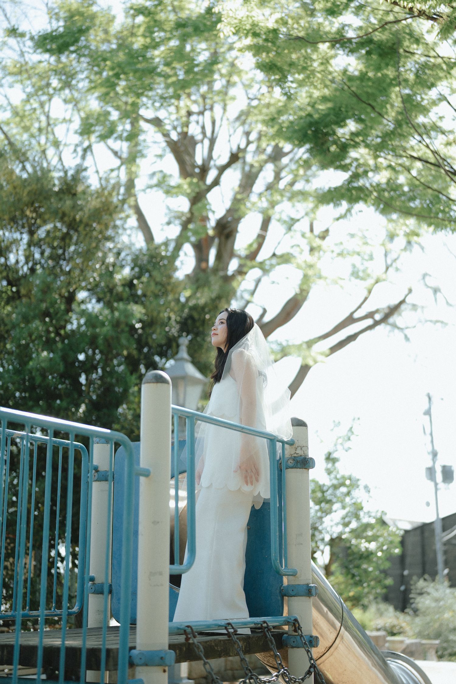 公園の木漏れ日の下でたたずむ女性のやさしいポートレート