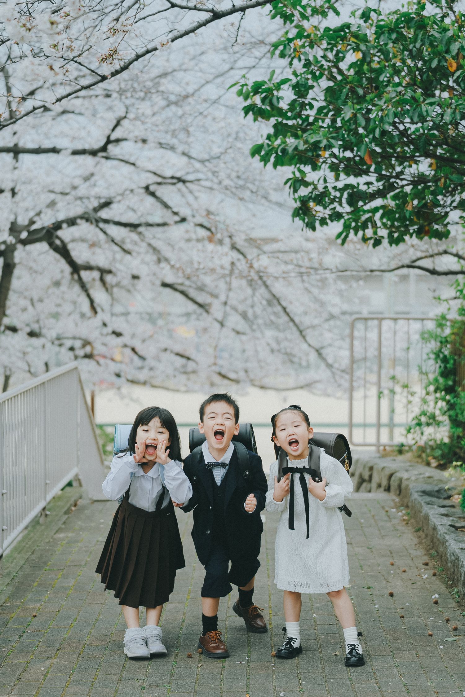 桜の咲く道で寄り添う子どもたちの記念写真