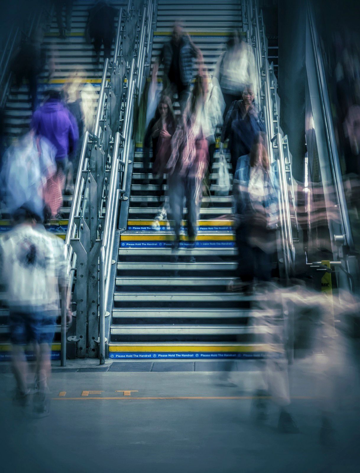 Street photograph of people at Leeds train station walking down the stairway in Leeds, capturing the movement, light and atmosphere