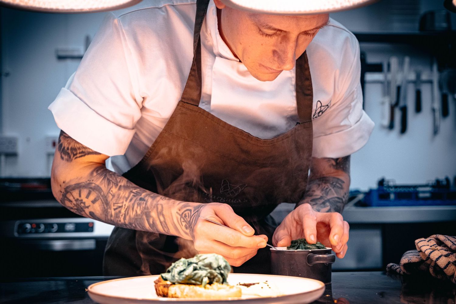 Food photograph of chef preparing pasta dish in Yorkshire kitchen, styled to highlight movement and detail