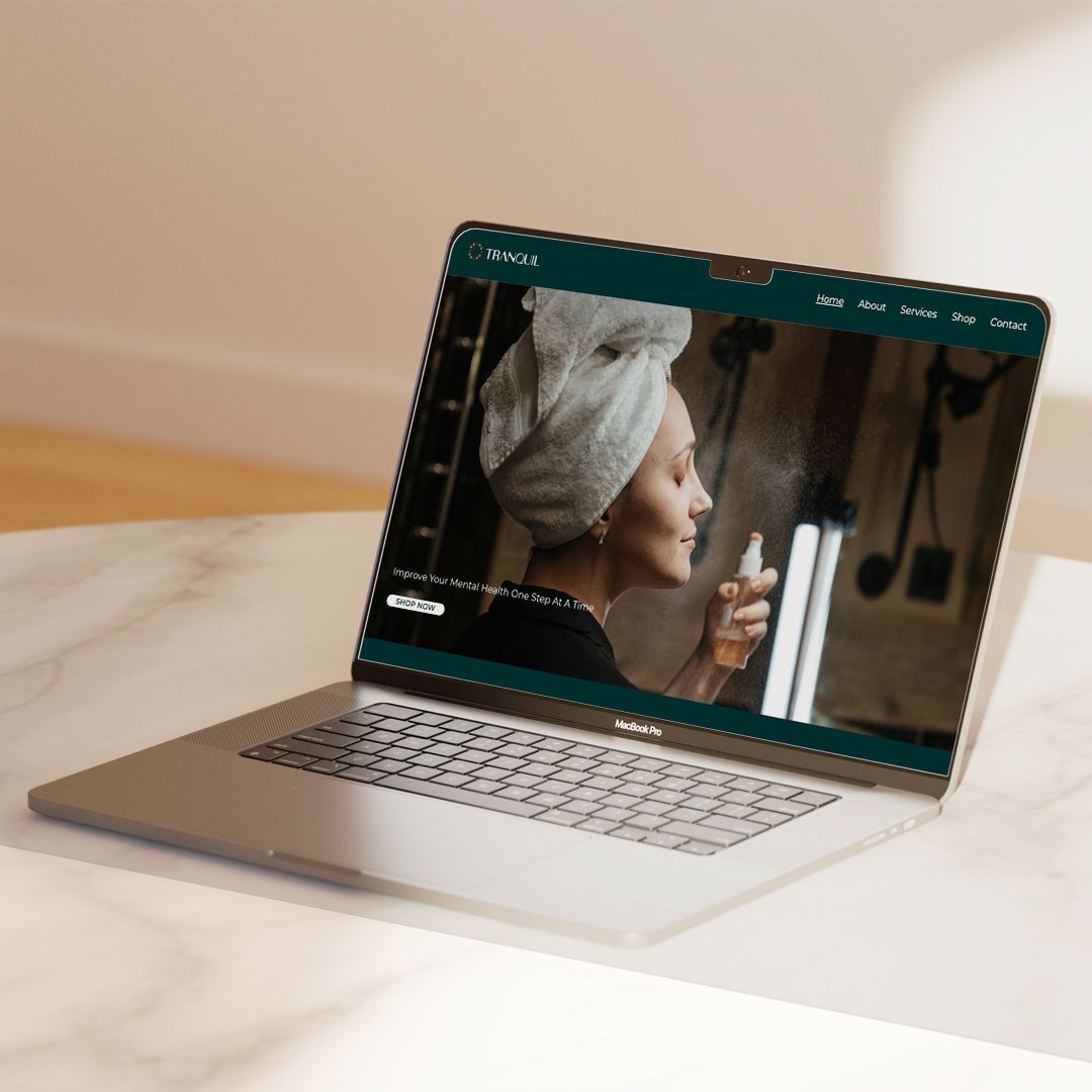 MacBook laptop on marble surface displaying Tranquil beauty brand website with woman skincare hero image.