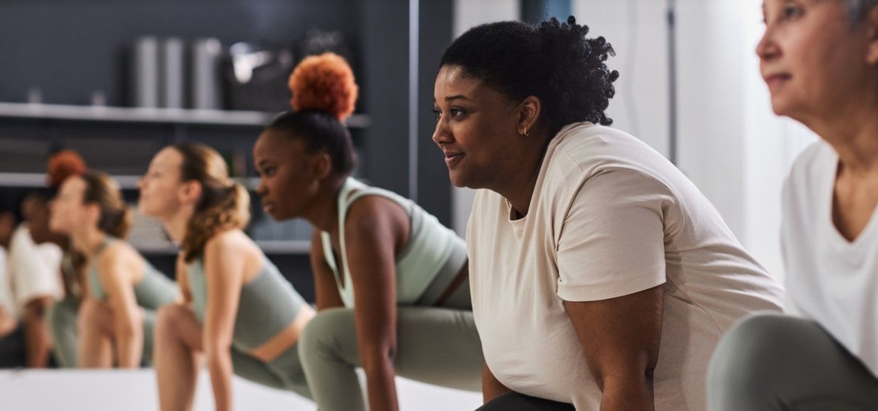 Diverse women practicing yoga poses in a bright fitness studio during a group workout class.