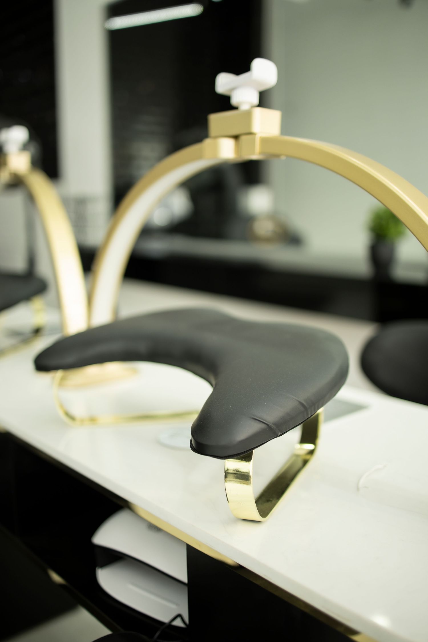 Luxury salon shampoo bowl with black leather cushion and gold arch frame on white marble counter.