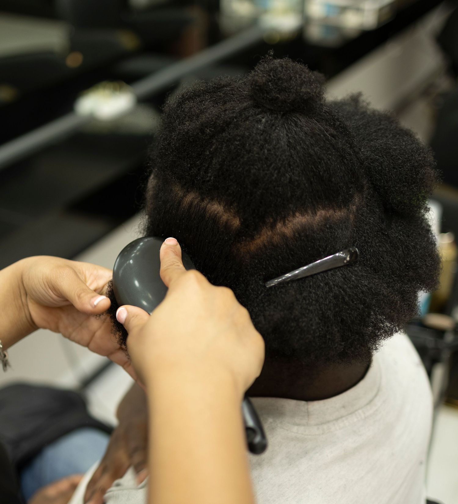 Hairstylist sectioning and combing natural Black hair in professional salon setting.