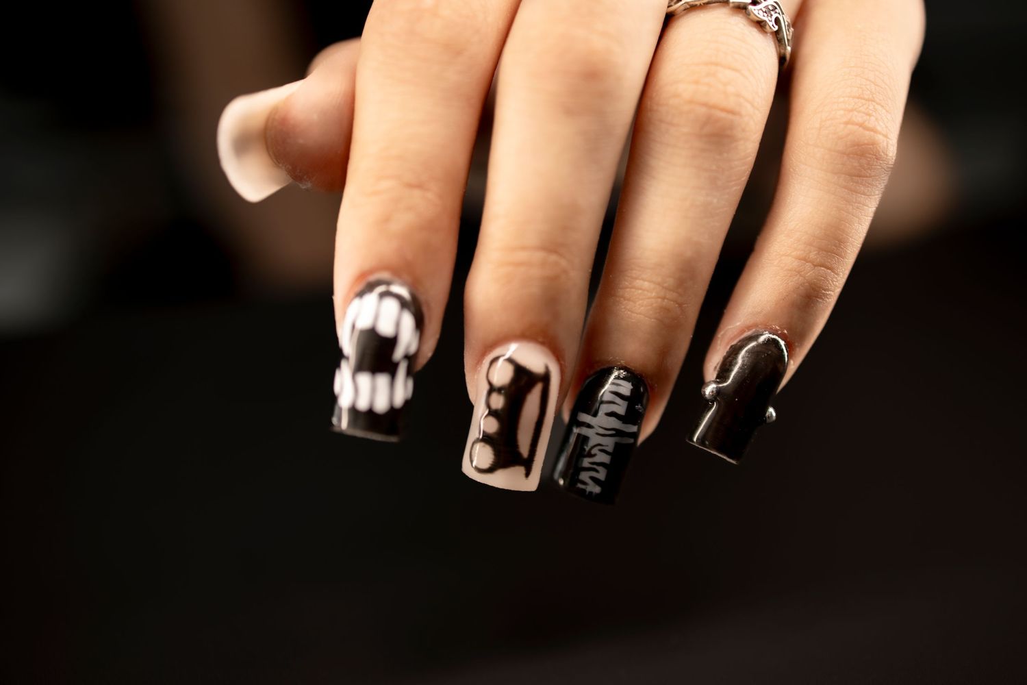 Black and white Halloween nail art featuring Batman logo, lace, and gothic designs on square acrylic nails.