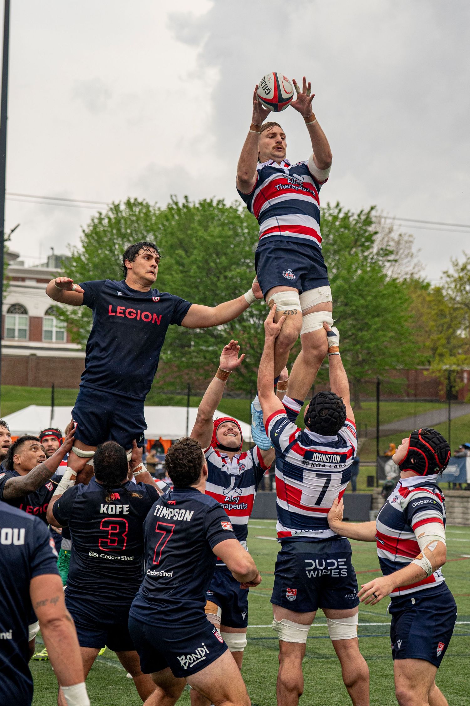 Rugby players compete in a lineout, with one player lifted high to catch the ball during a match.