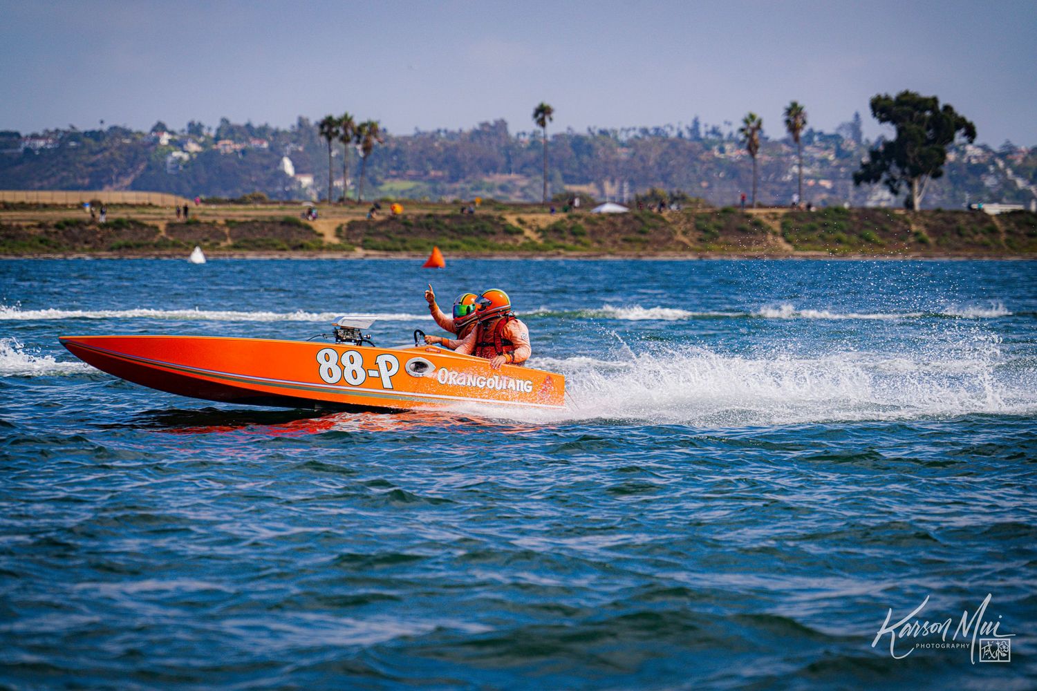 Orange racing boat numbered 88-P speeds across blue water during a competitive powerboat racing event.