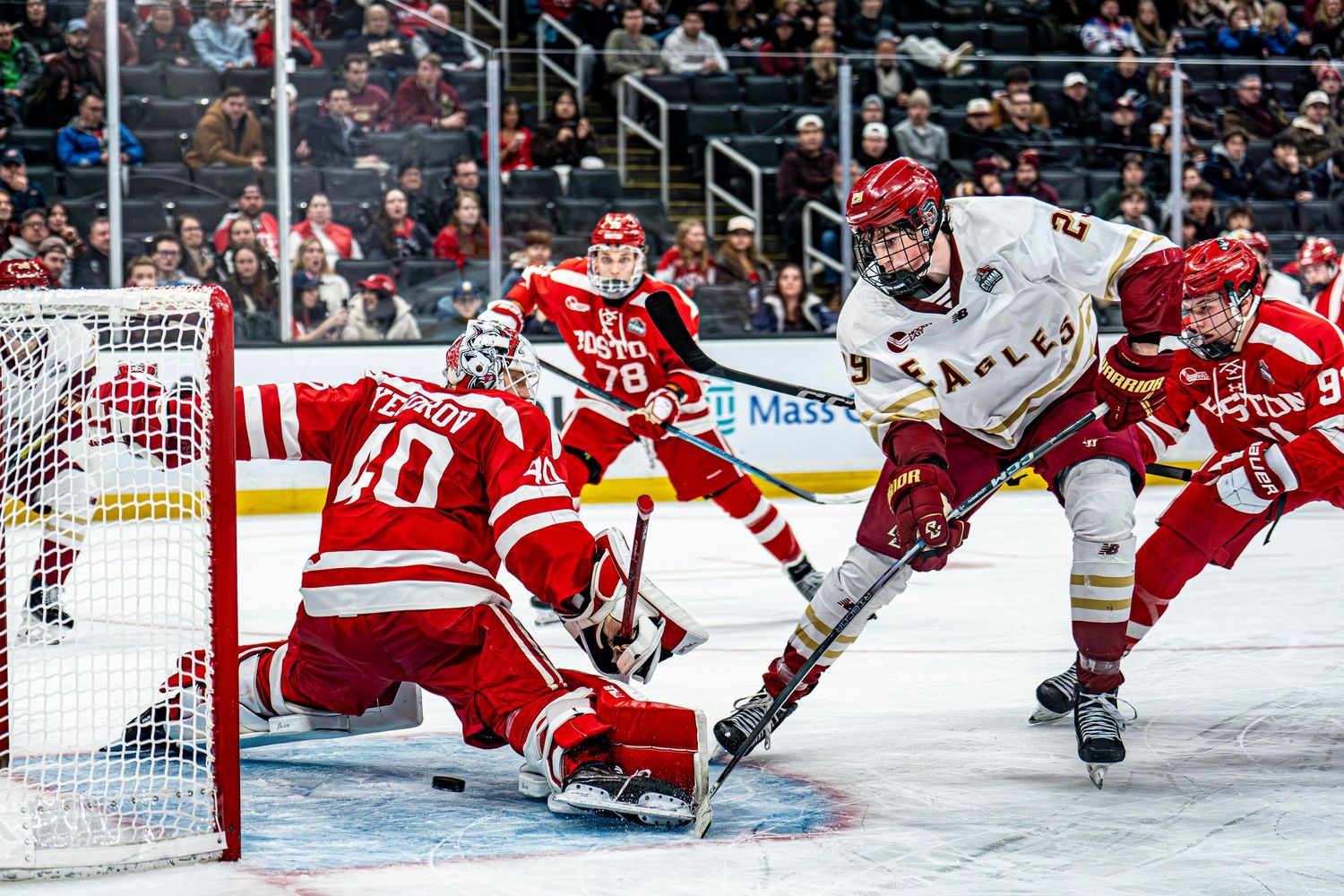 Boston College Eagles player attempts shot on goal against Boston University Terriers goalie.