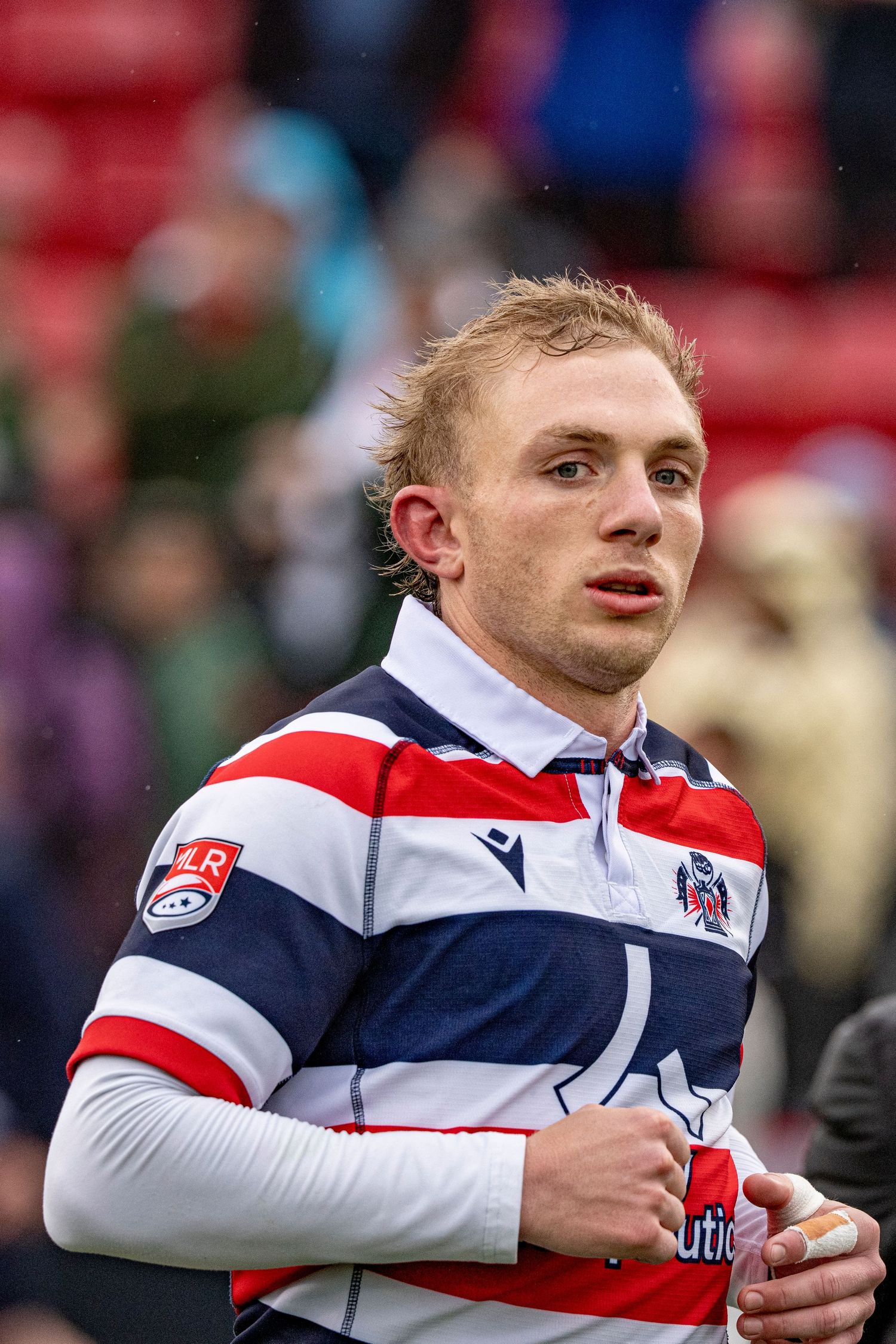Young rugby player in red, white, and blue striped jersey during a match.