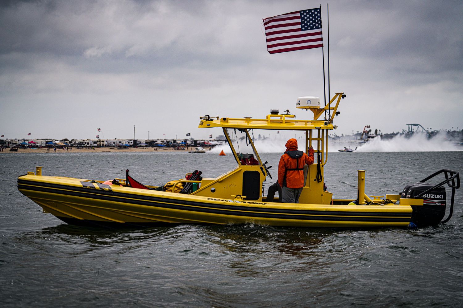 Yellow US Coast Guard rigid inflatable boat patrols a choppy waterway under cloudy skies.