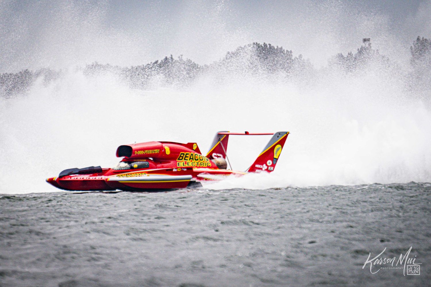 Red hydroplane racing boat speeds through mist and spray during an intense competitive powerboat race.