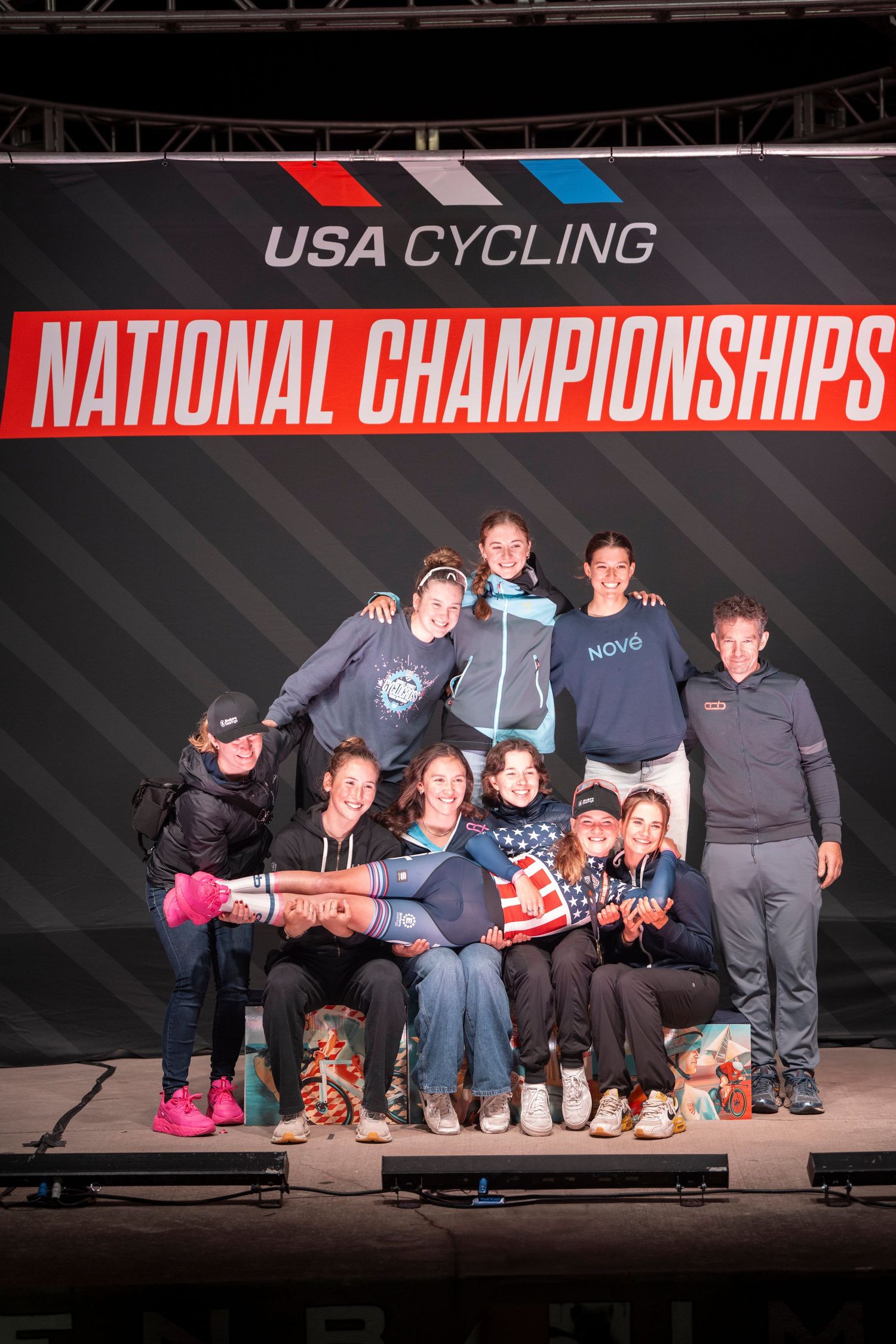 Group of female cyclists pose together on stage at USA Cycling National Championships event.