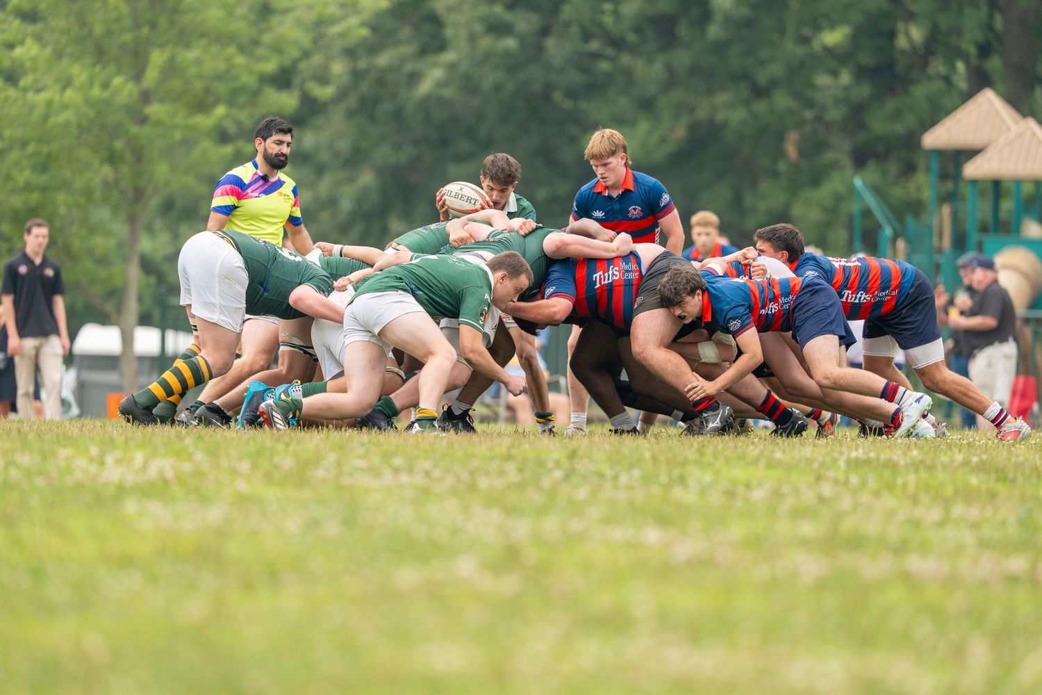 Rugby players compete in an intense scrum during an outdoor match on a grass field.