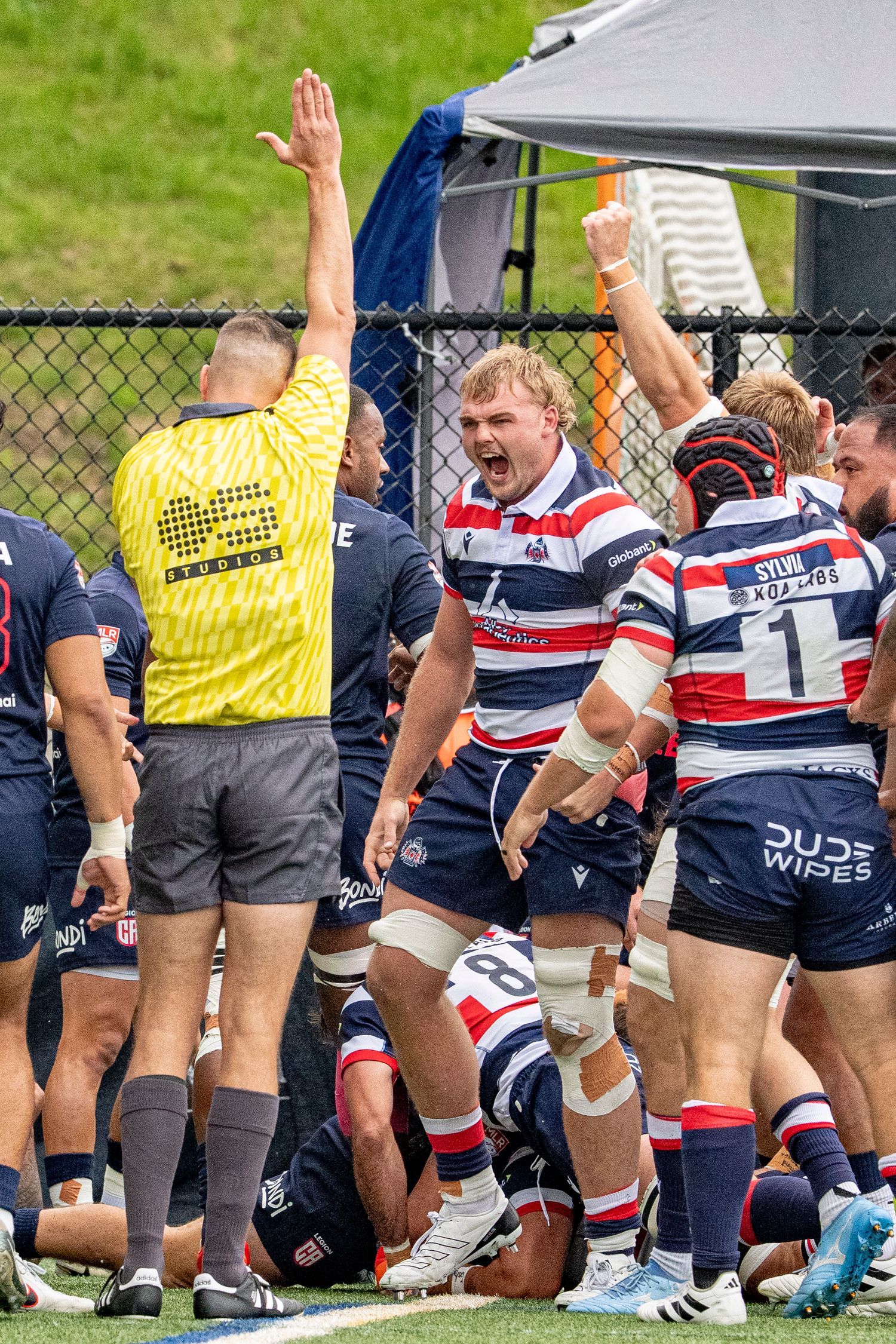 Rugby players celebrate a try as a referee signals the score during an outdoor match.